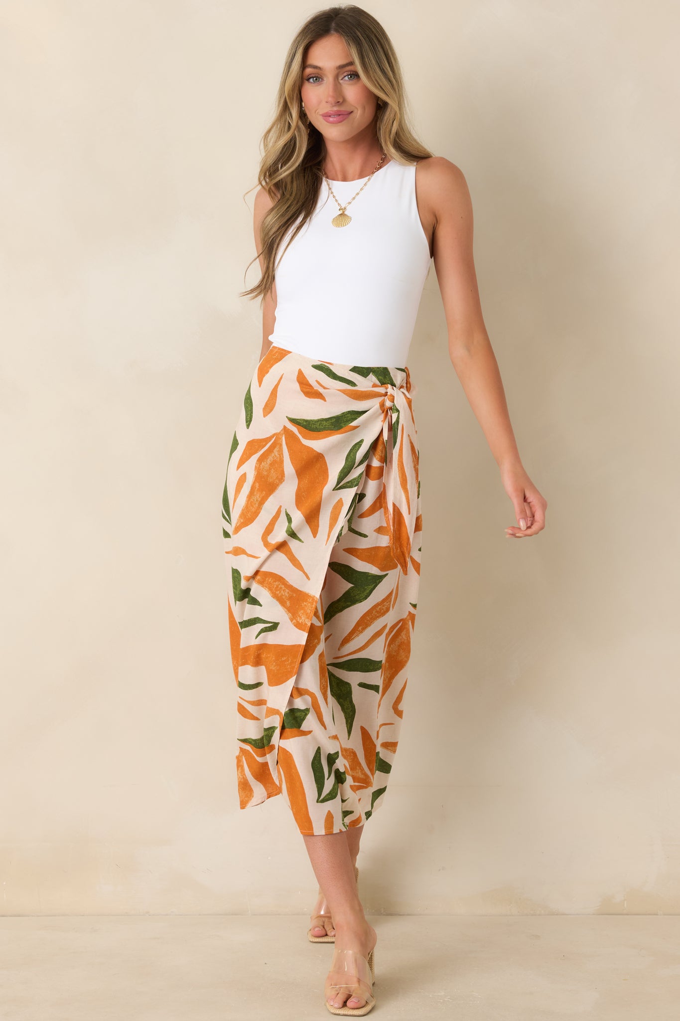 Tropical print midi skirt featuring orange and green hues with adjustable self-tie wrap closure.