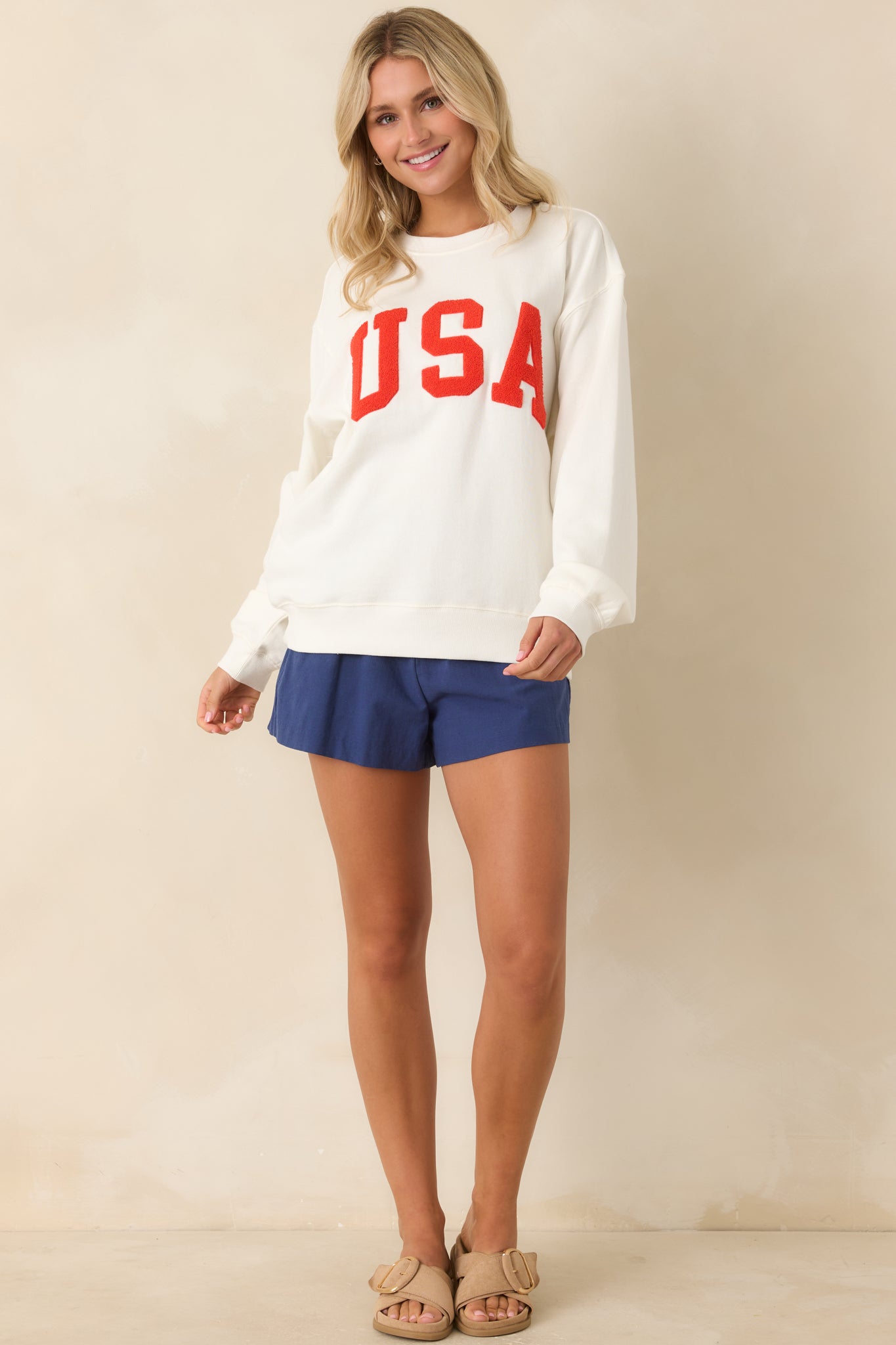 Full-length look showing the crew neckline, long sleeves, and casual fit with textured lettering as the main focal point.