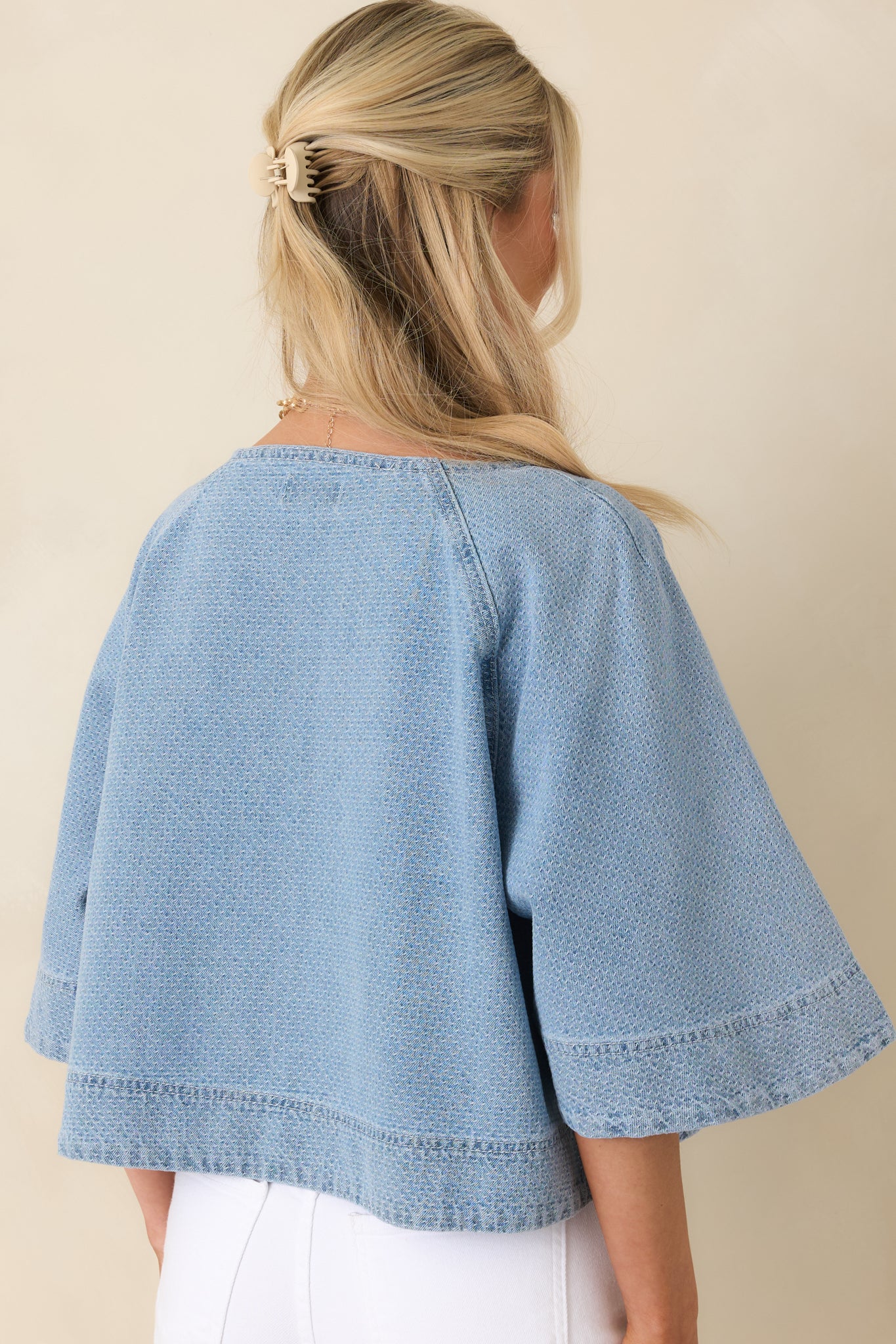 Rear view of light wash cropped denim top with boxy silhouette and short sleeves.