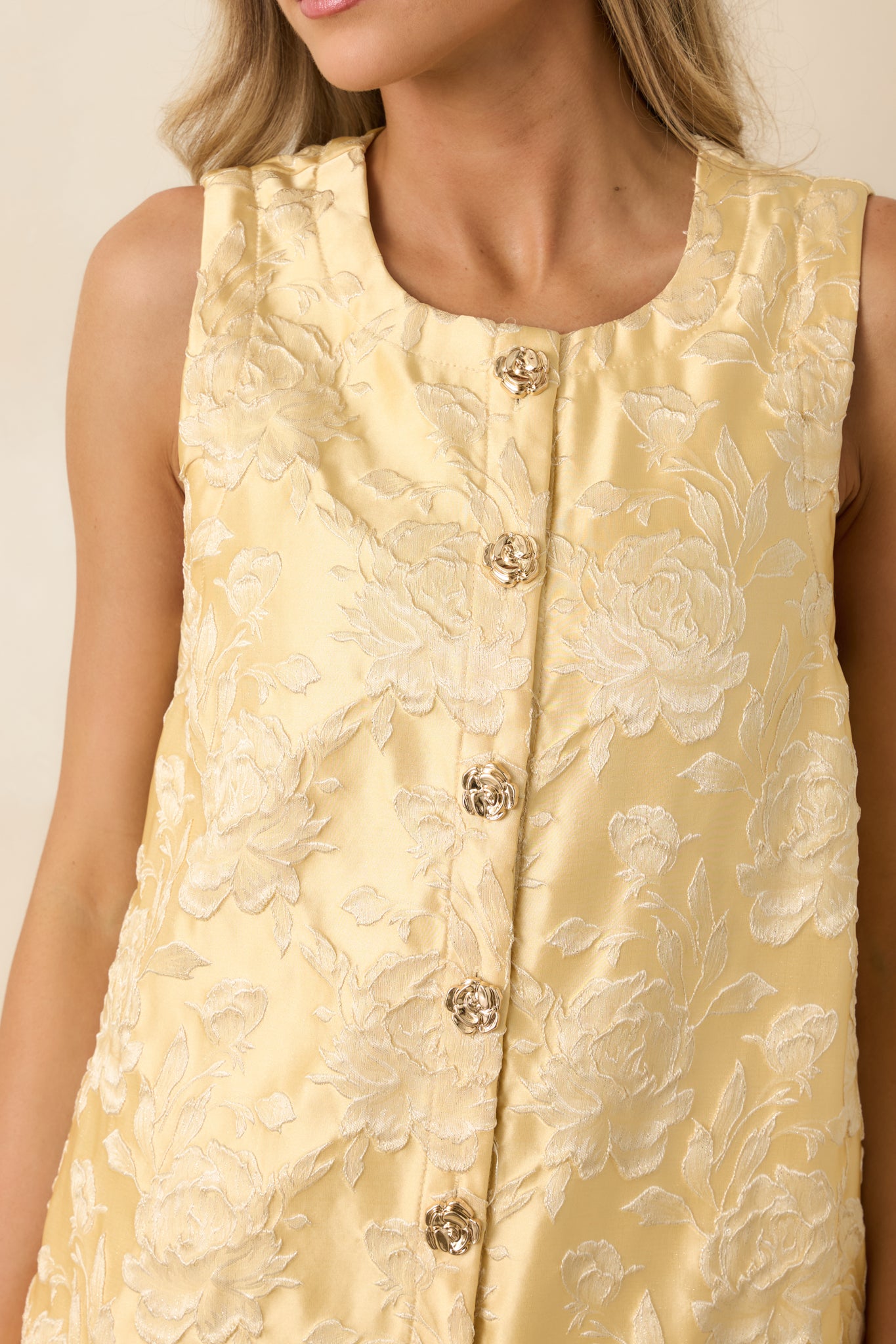 Detailed view of gold flower buttons and floral jacquard texture with metallic finish.