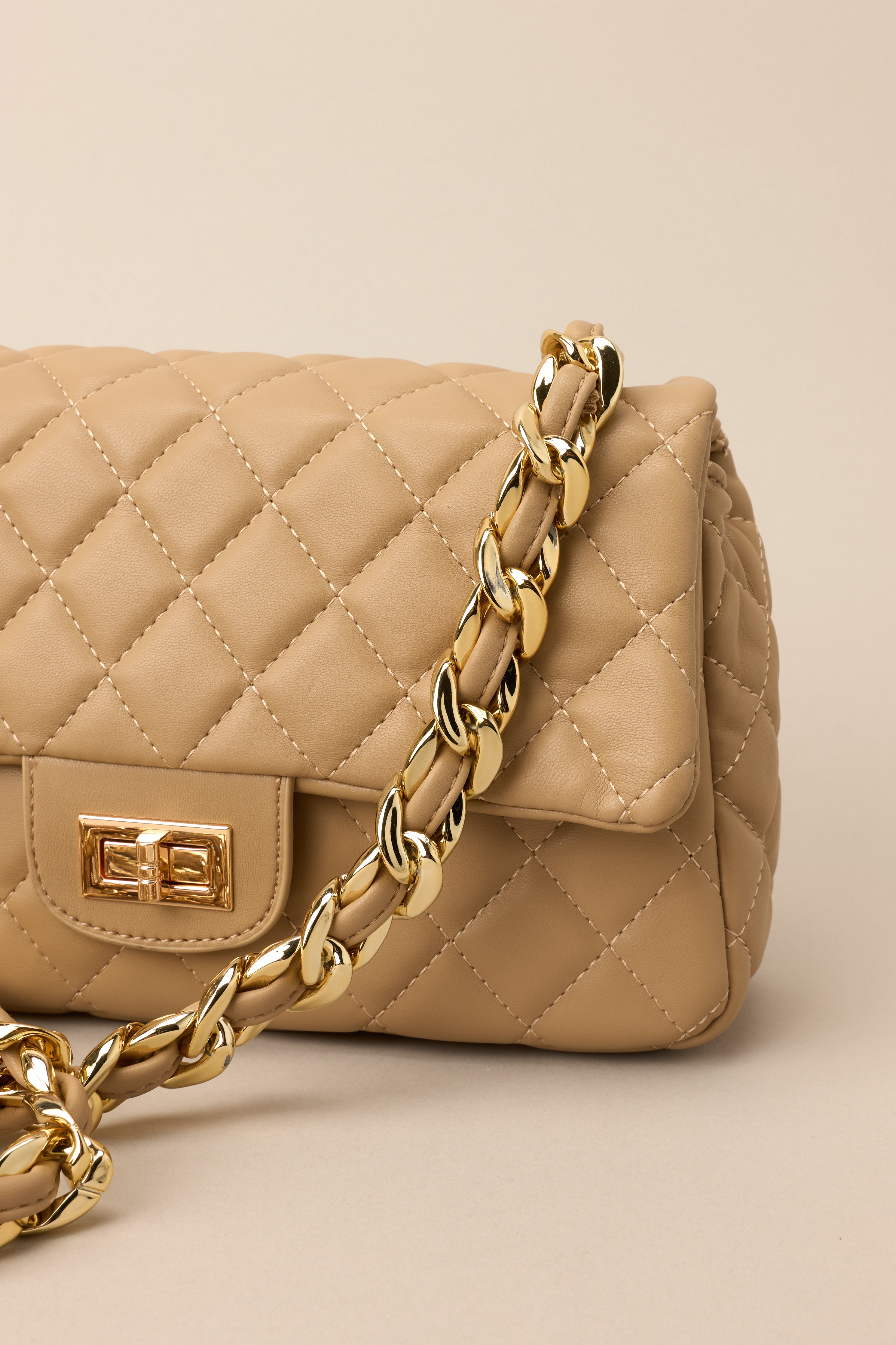 Close cropped angle showing chain strap detail and gold hardware on quilted bag