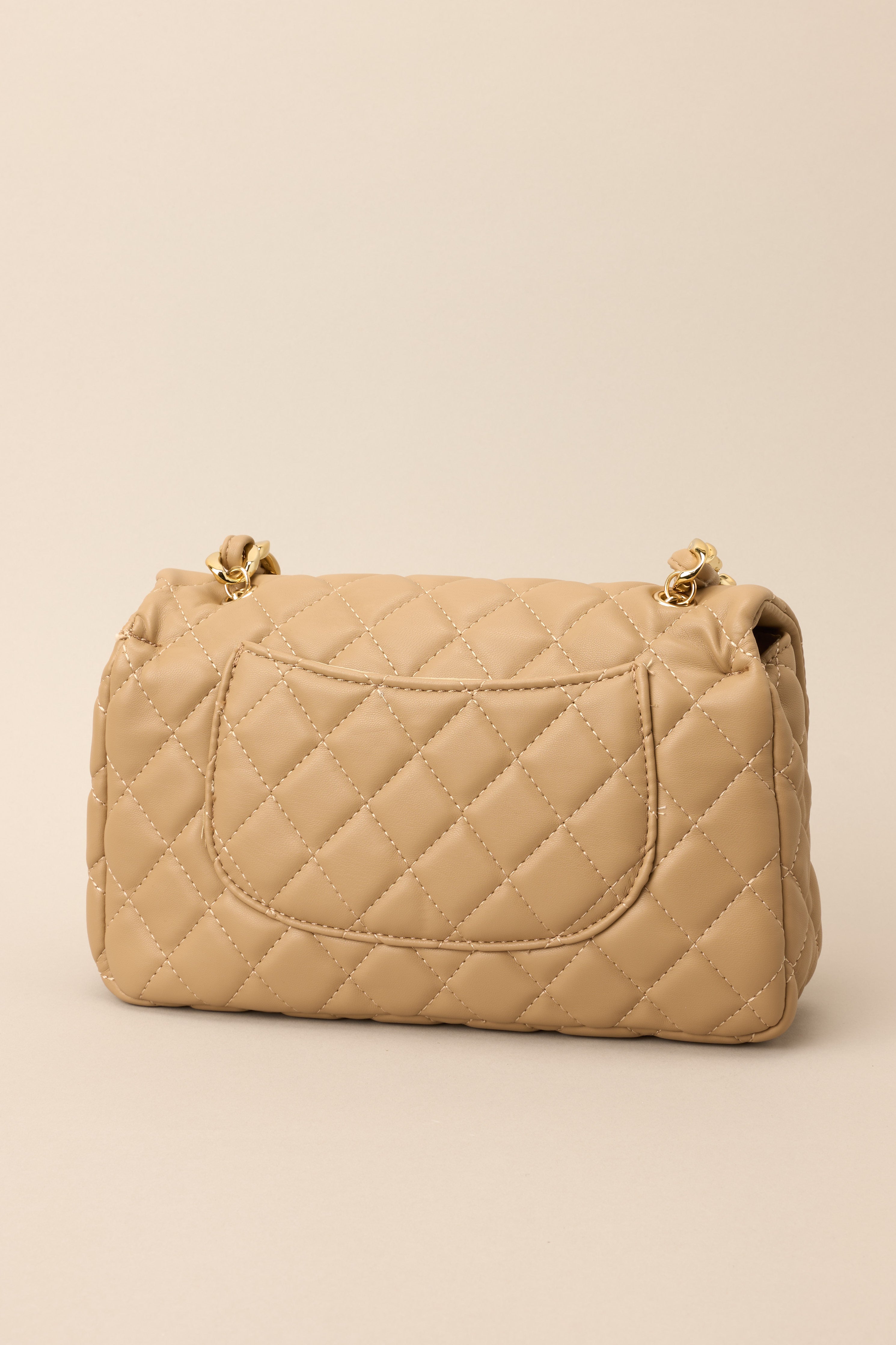 Back view of tan quilted handbag highlighting smooth rear panel and compact, structured shape