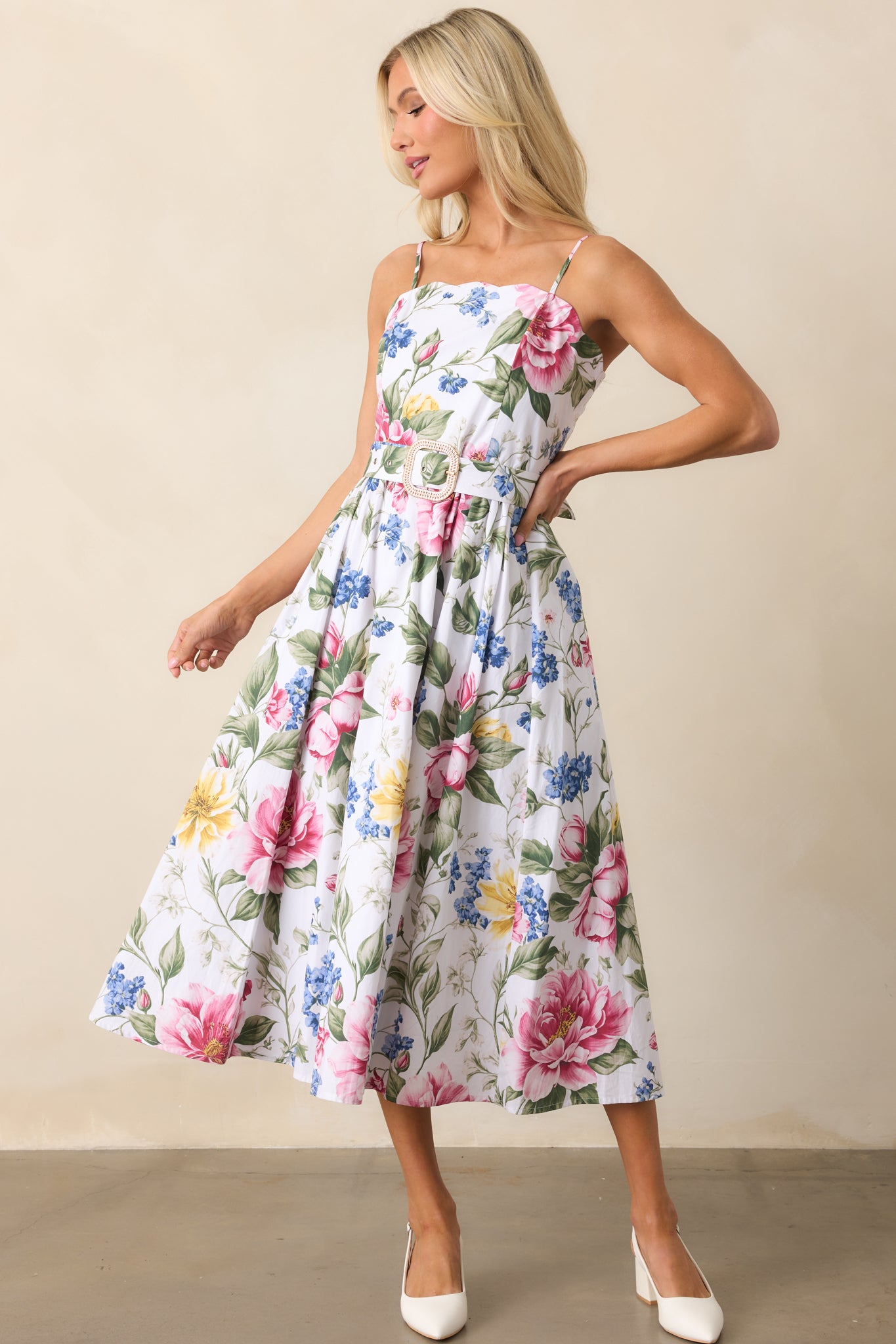 A midi dress with a multicolor floral print, a scalloped neckline, and adjustable straps for a delicate, feminine look.