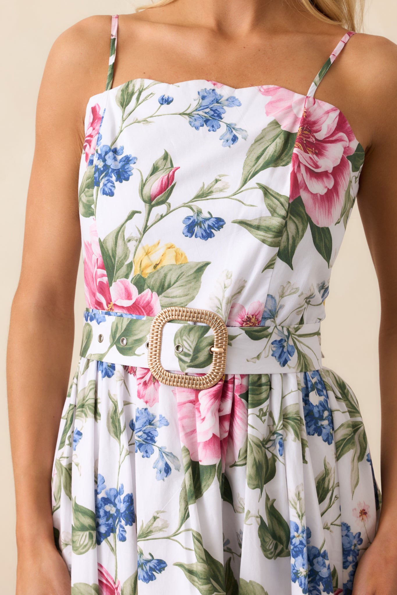 A close-up of the midi dress highlighting the scalloped neckline, intricate floral print, and optional gold-buckled belt.