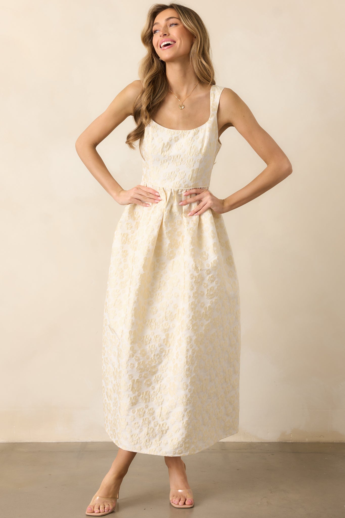 A charming butter yellow dress showcasing a scoop neckline, a tailored bodice, and a flowing structured skirt with floral detailing.