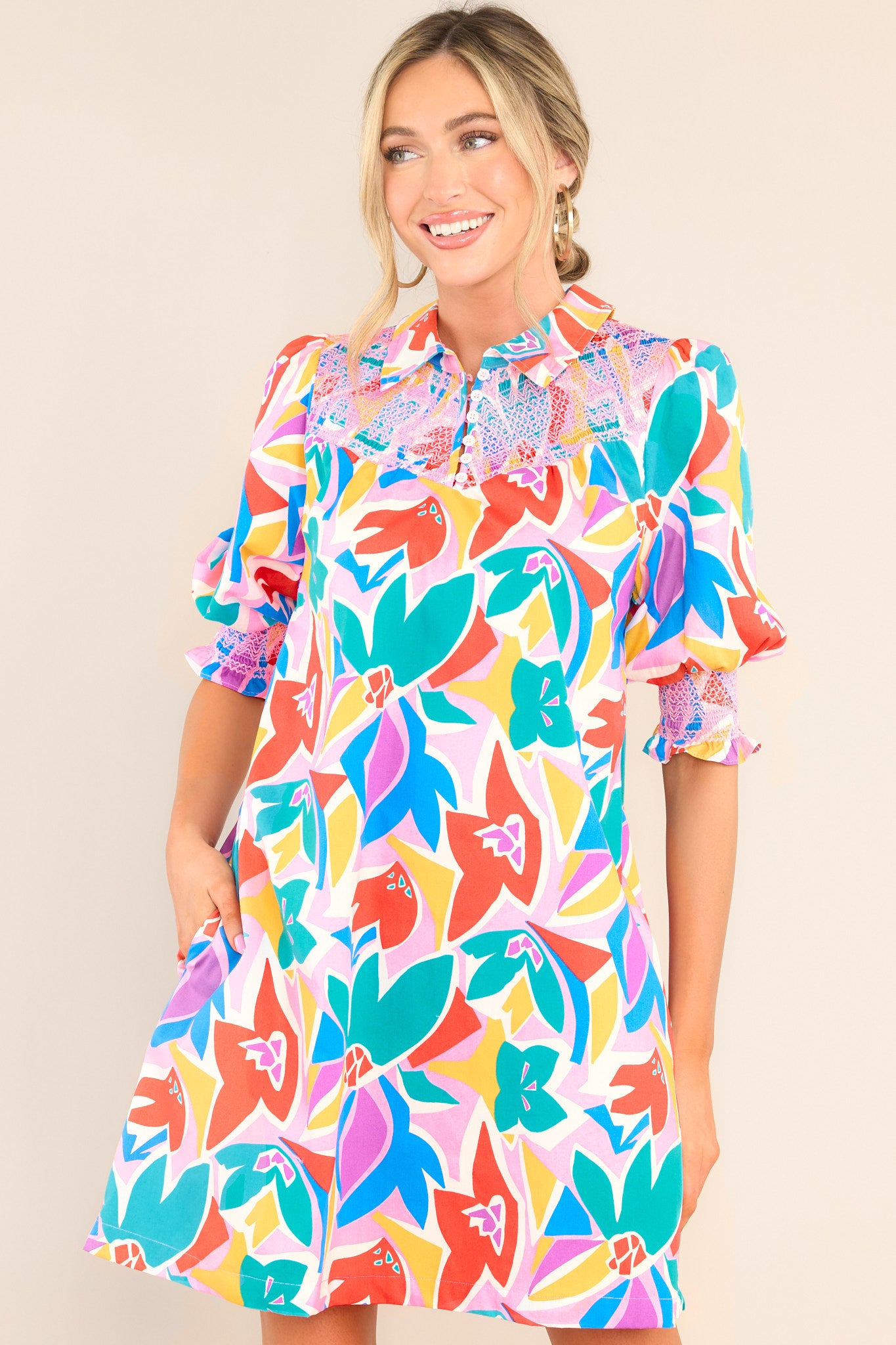 Front view of this dress that features a collared neckline, a smocked chest insert, functional buttons & pockets, and thick elastic cuffed sleeves.