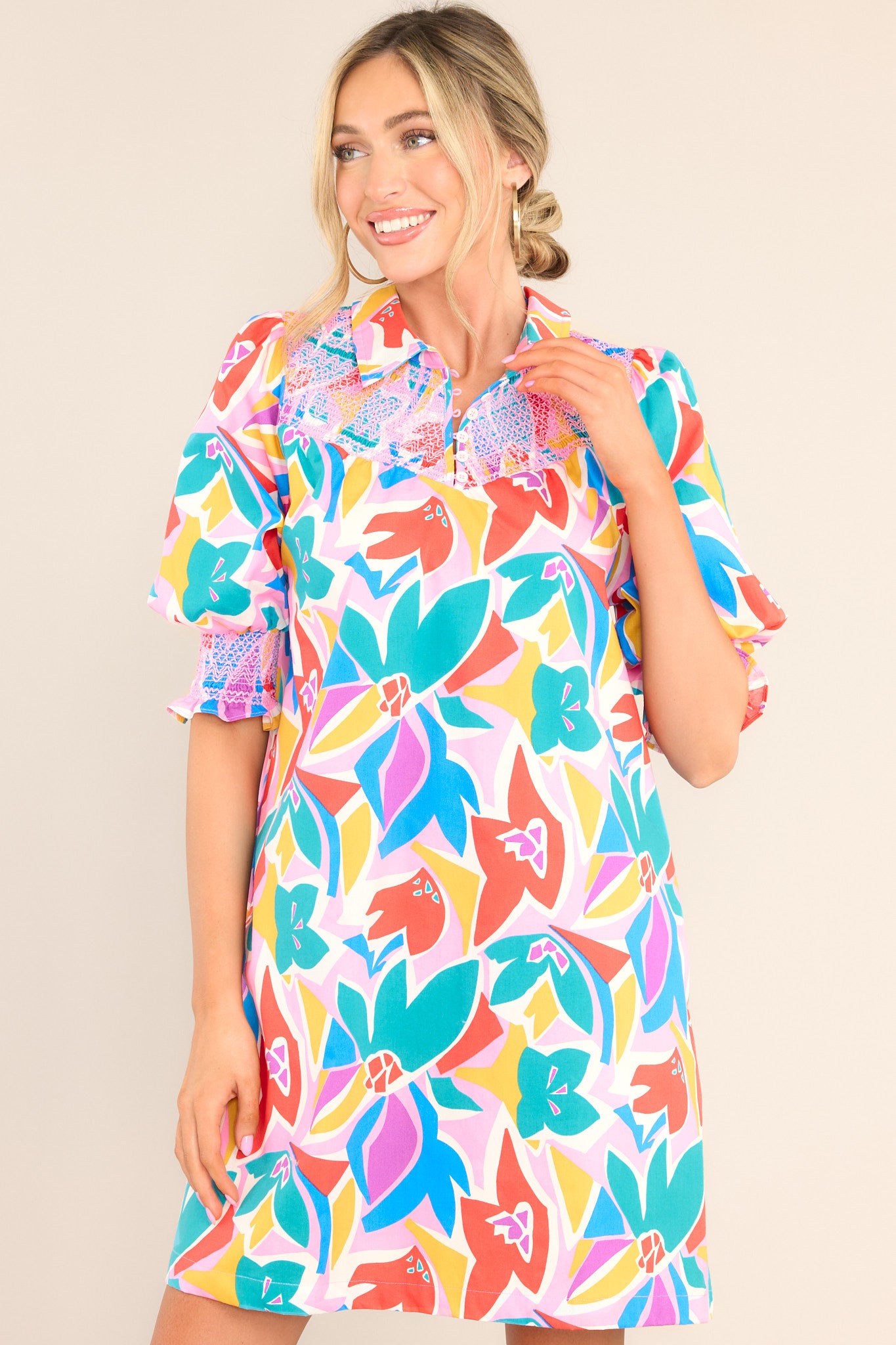 Full front view of this dress that features a collared neckline, a smocked chest insert, functional buttons & pockets, and thick elastic cuffed sleeves.