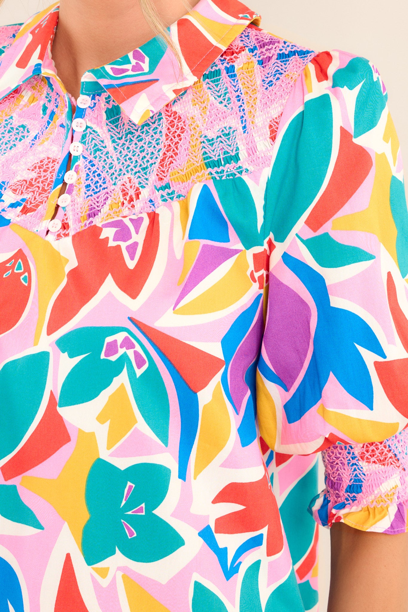 Close up view of this dress that features a collared neckline, a smocked chest insert, functional buttons & pockets, and thick elastic cuffed sleeves.