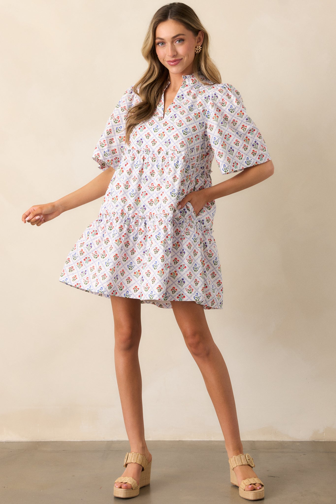 A light blue mini dress with a criss-cross grid print and multicolor floral motifs, featuring a notch v-neckline and short sleeves.