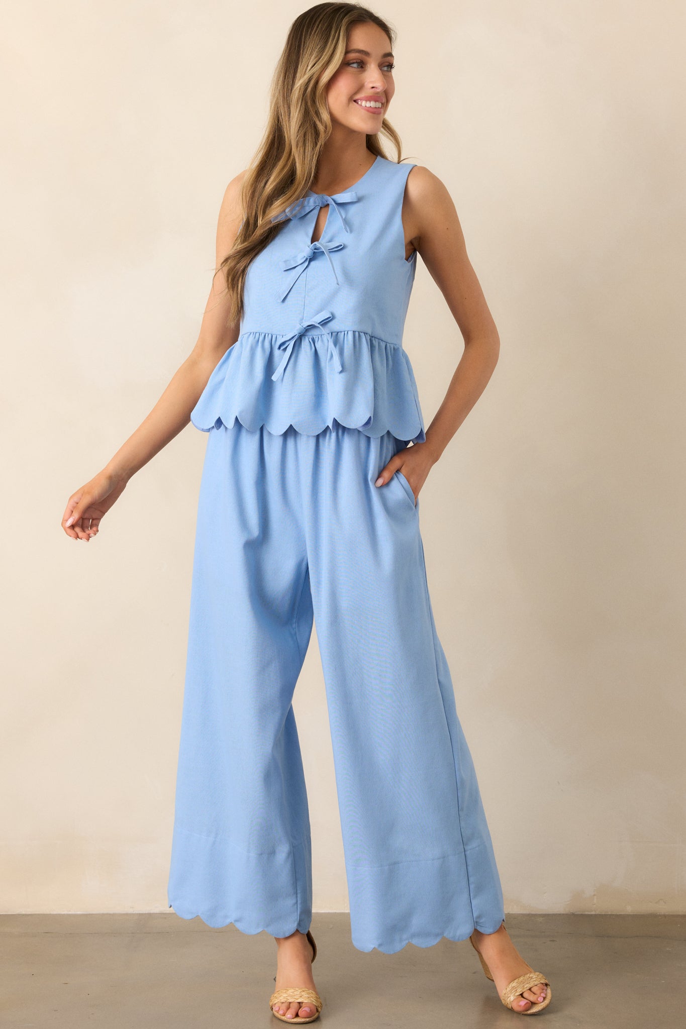 A stylish pair of light blue pants with a high waist, wide leg cut, and scalloped hem, complete with functional pockets.