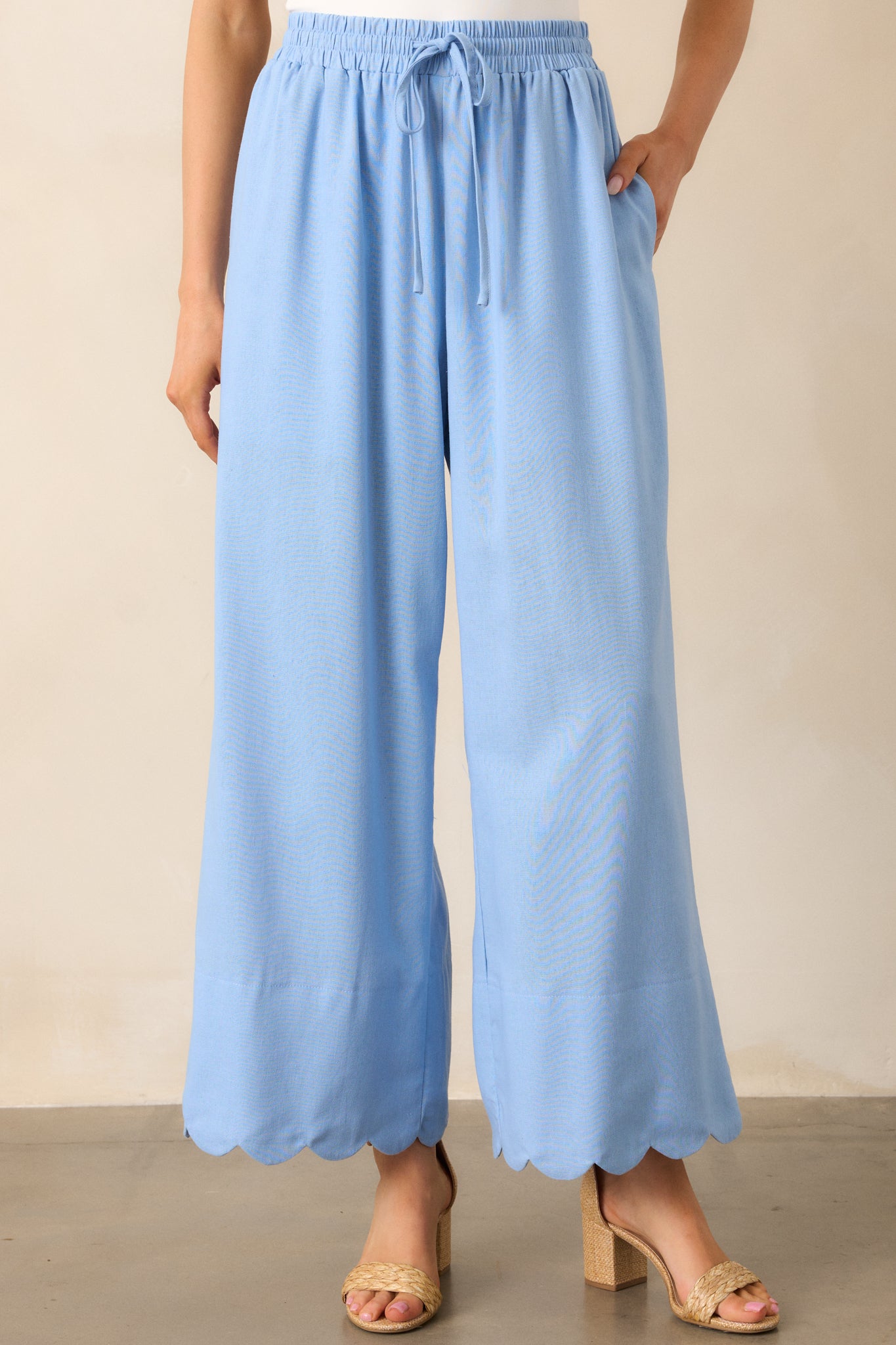 These light blue pants highlight the scalloped hem and functional pockets, paired with a high-waist, wide-leg silhouette.