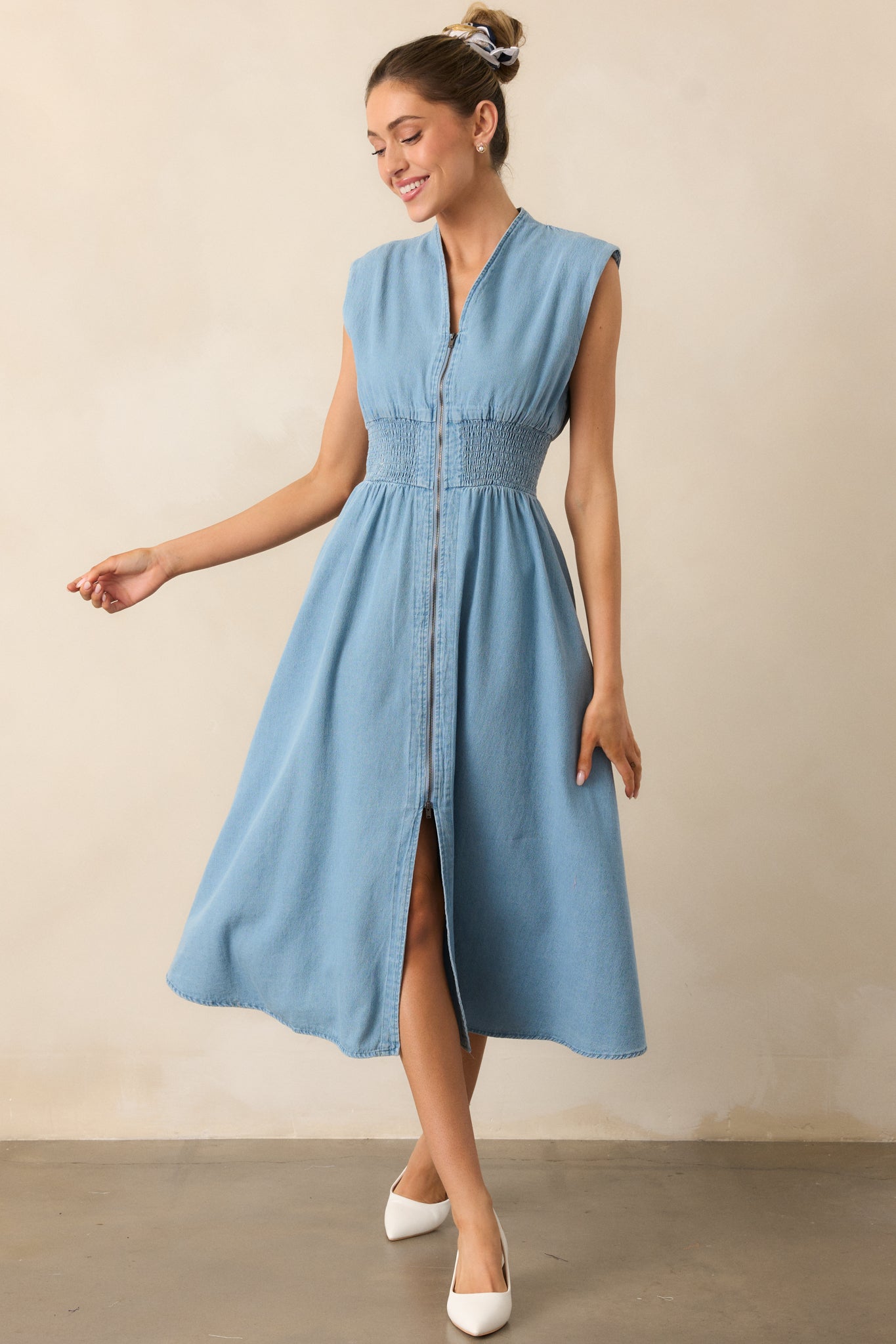 This light wash midi dress has a v-neckline and lightly padded shoulders for structure. The smocked waist provides a flattering fit, complemented by functional hip pockets and a front slit that adds an element of movement.