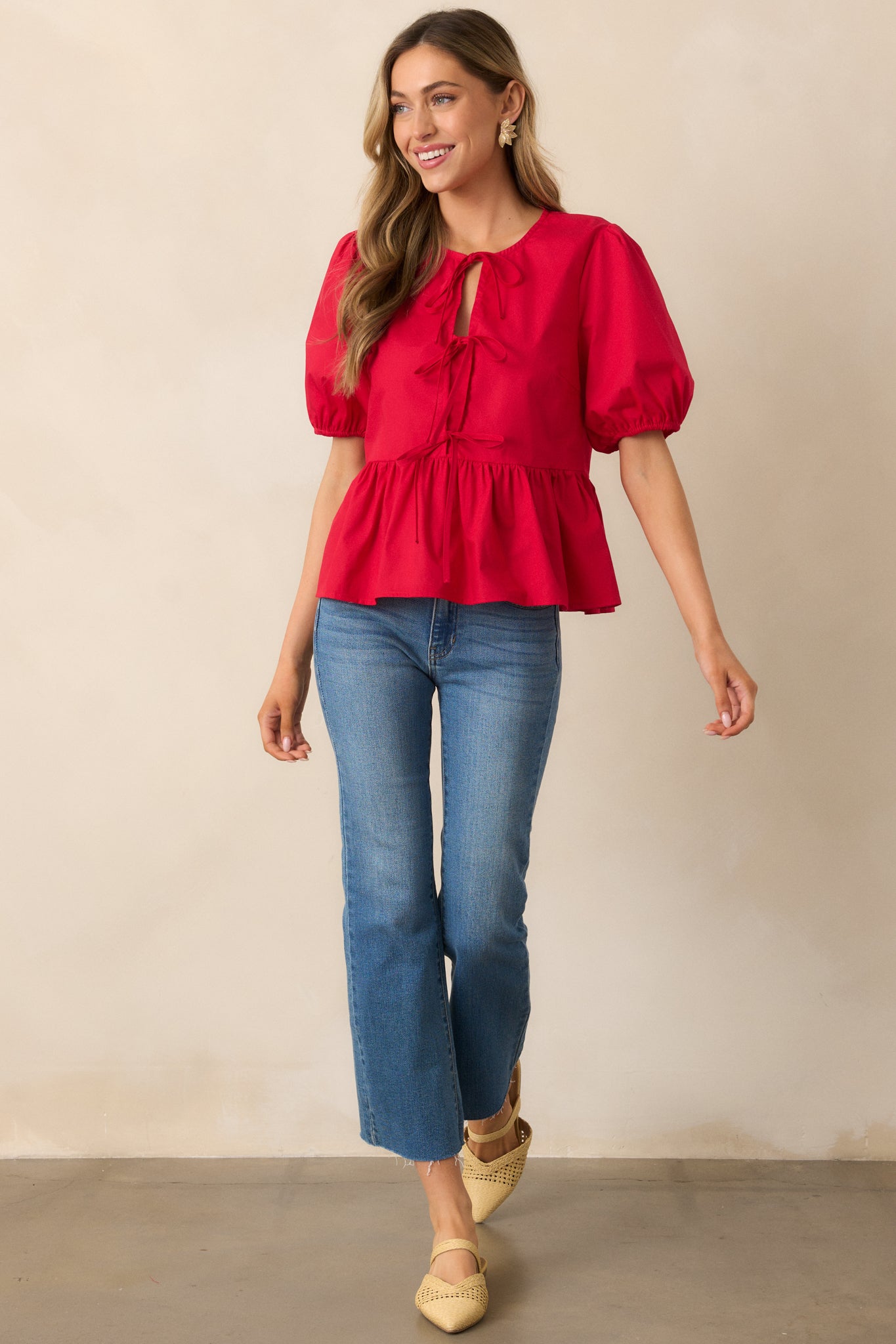 A charming red top with a round neckline, self-tie bow details, and a peplum-style hem, offering a sweet, retro-inspired silhouette.