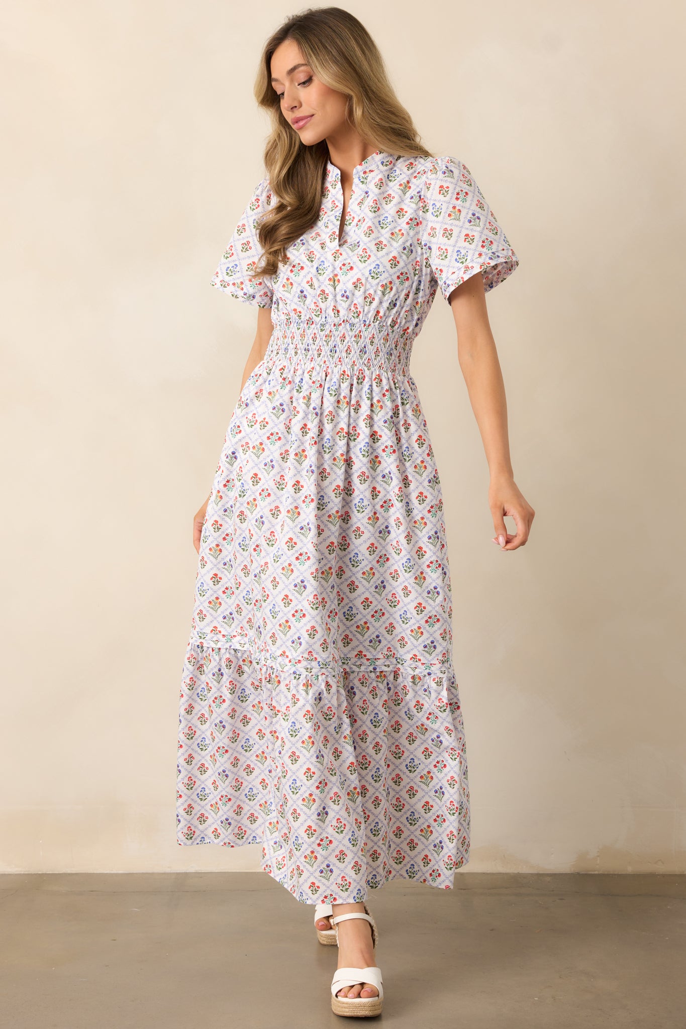 A light blue maxi dress with a v-neckline, short sleeves, and intricate pin tuck detailing, highlighting the multicolor floral motifs in the grid pattern.