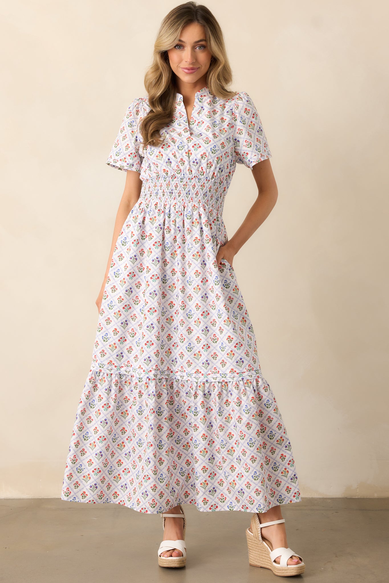 A view of the light blue maxi dress featuring a grid print with colorful flowers, a smocked waist, and a v-neckline, complete with short sleeves and pin tuck accents.