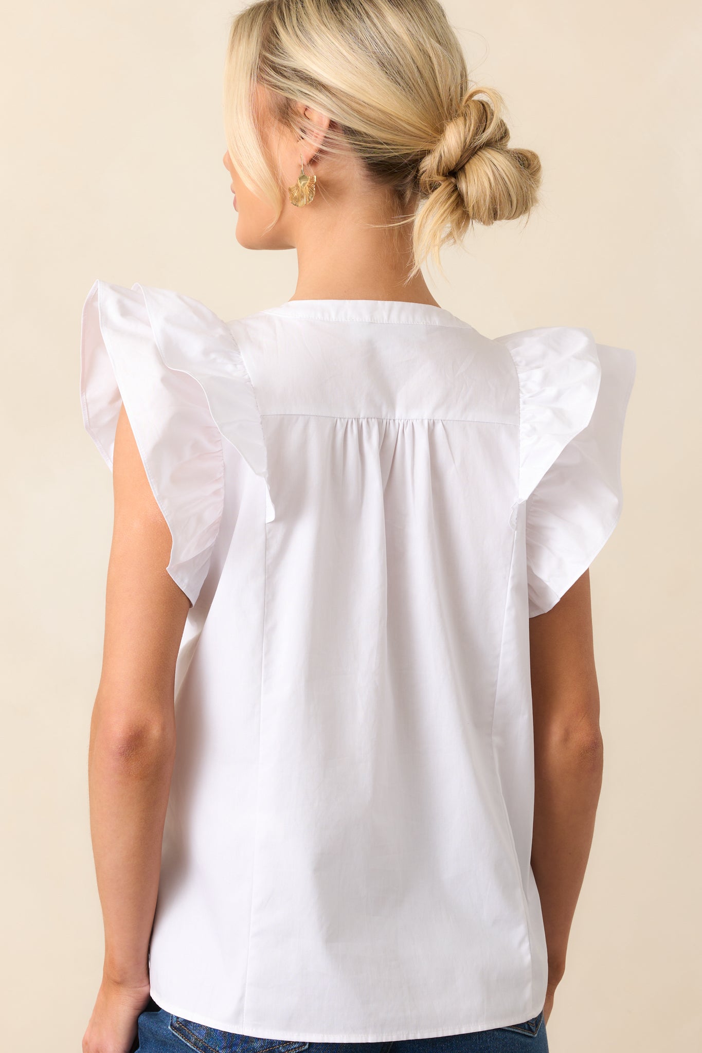 The back of the white top, showcasing its clean lines and simple, versatile style that pairs easily with various outfits.