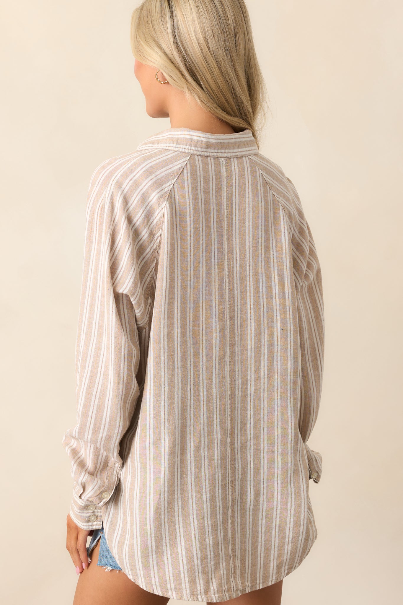 A view from behind of the taupe top showing the long sleeves, subtle drape, and clean back panel.