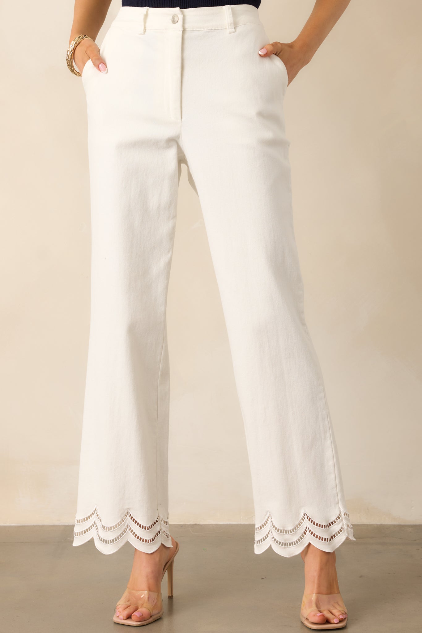 A zoomed-in shot of the functional front pockets, highlighting the delicate embroidered eyelet details on the scalloped bottom hems and the structured high waist design.