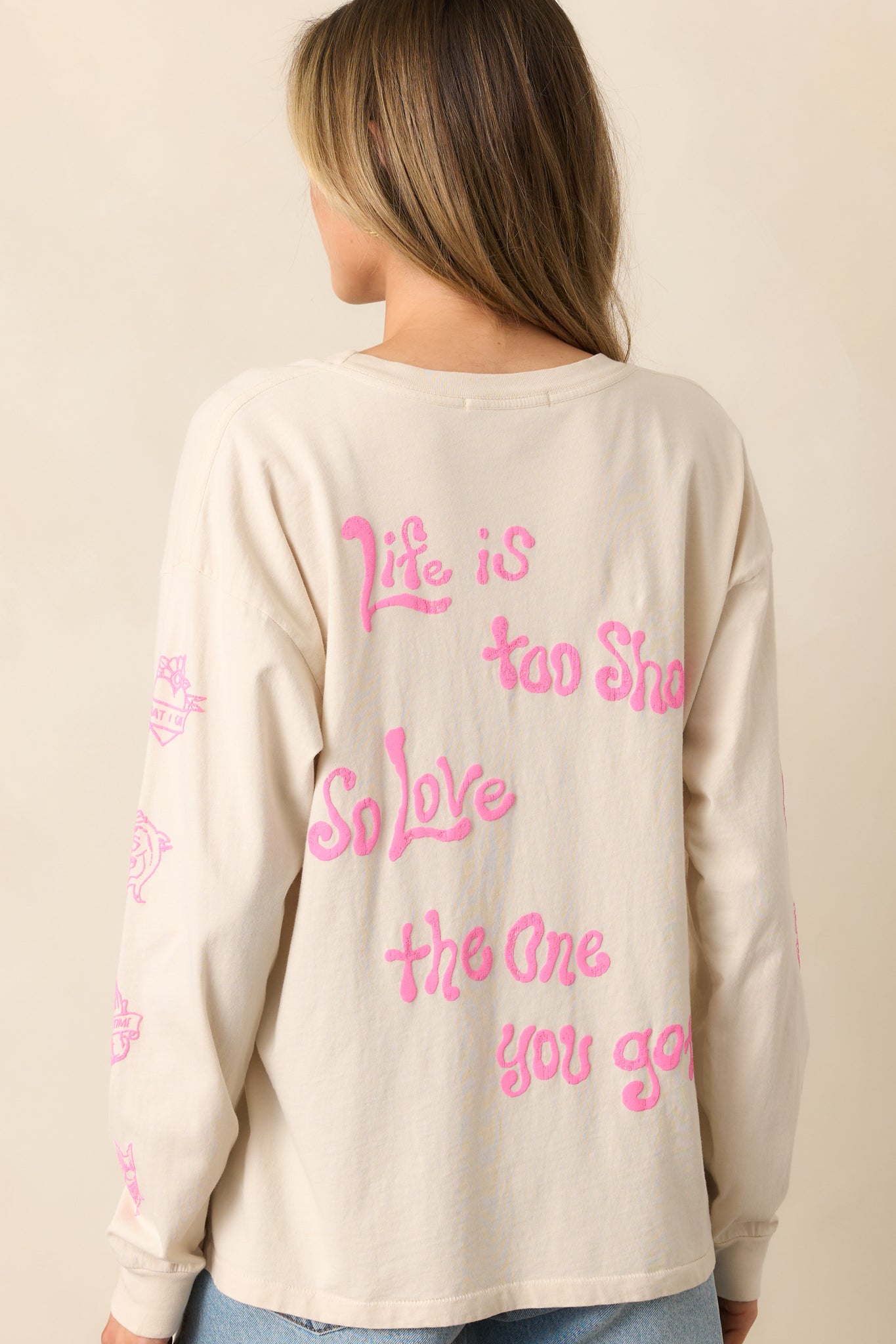 The rear view of the white tee reveals the clean design, highlighting the soft fabric and ribbed hemlines, with a smooth finish complementing the bold graphic print on the front.