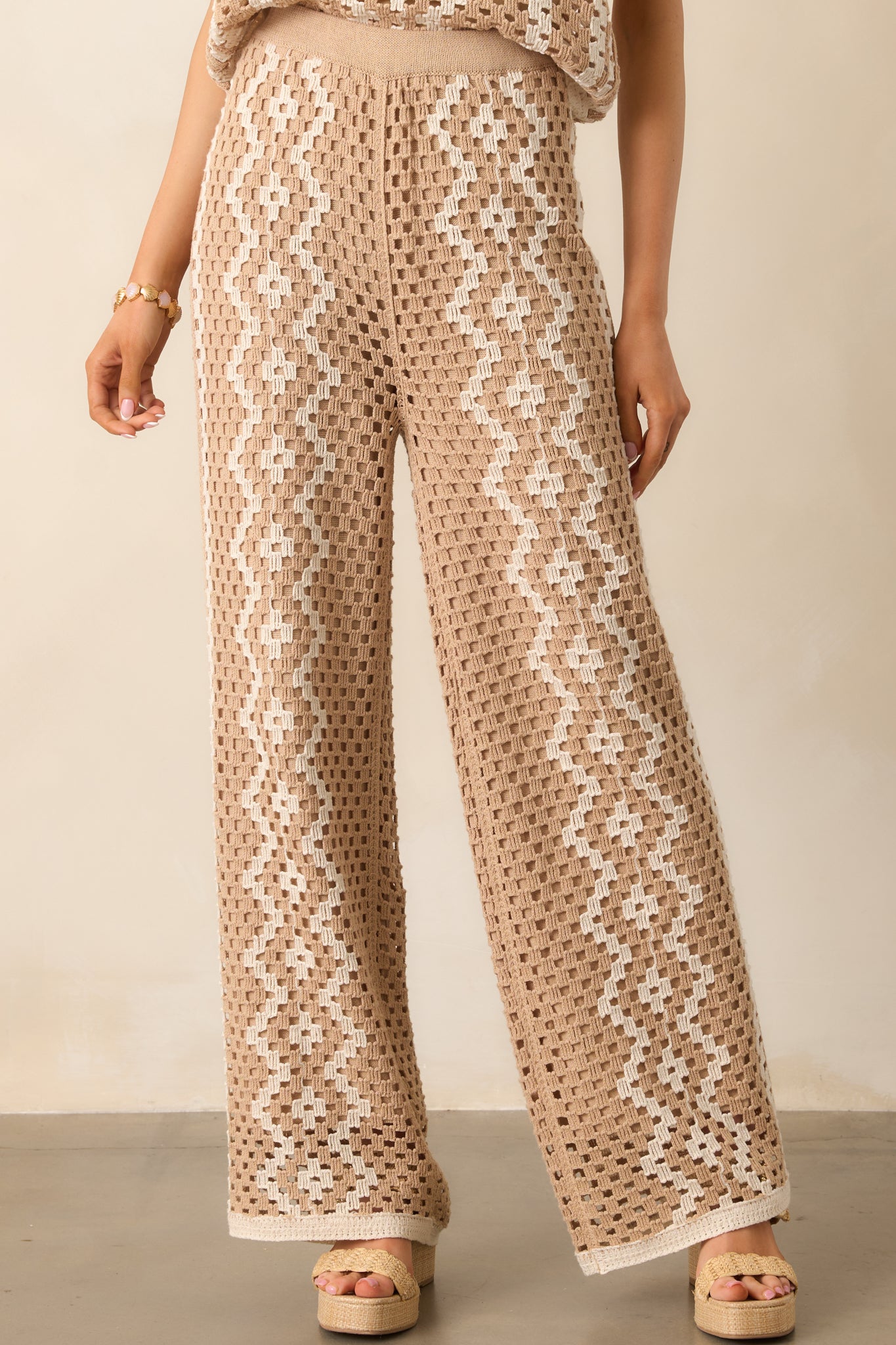 Close-up of the elastic waistband and geometric pattern of the tan and ivory crochet pants.