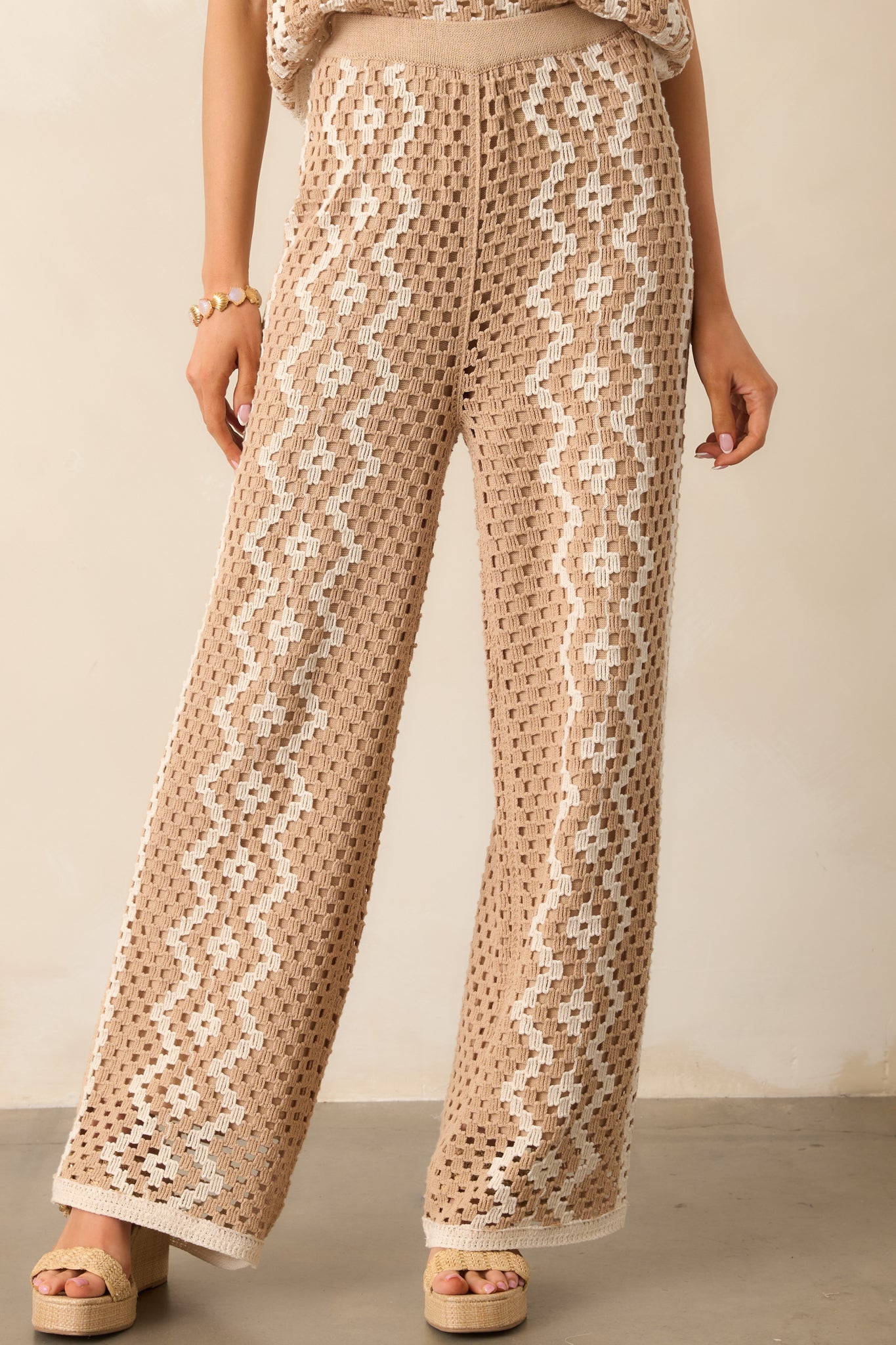 Close-up of the tan and ivory geometric crochet fabric, showcasing the intricate pattern and cotton texture of the pants.