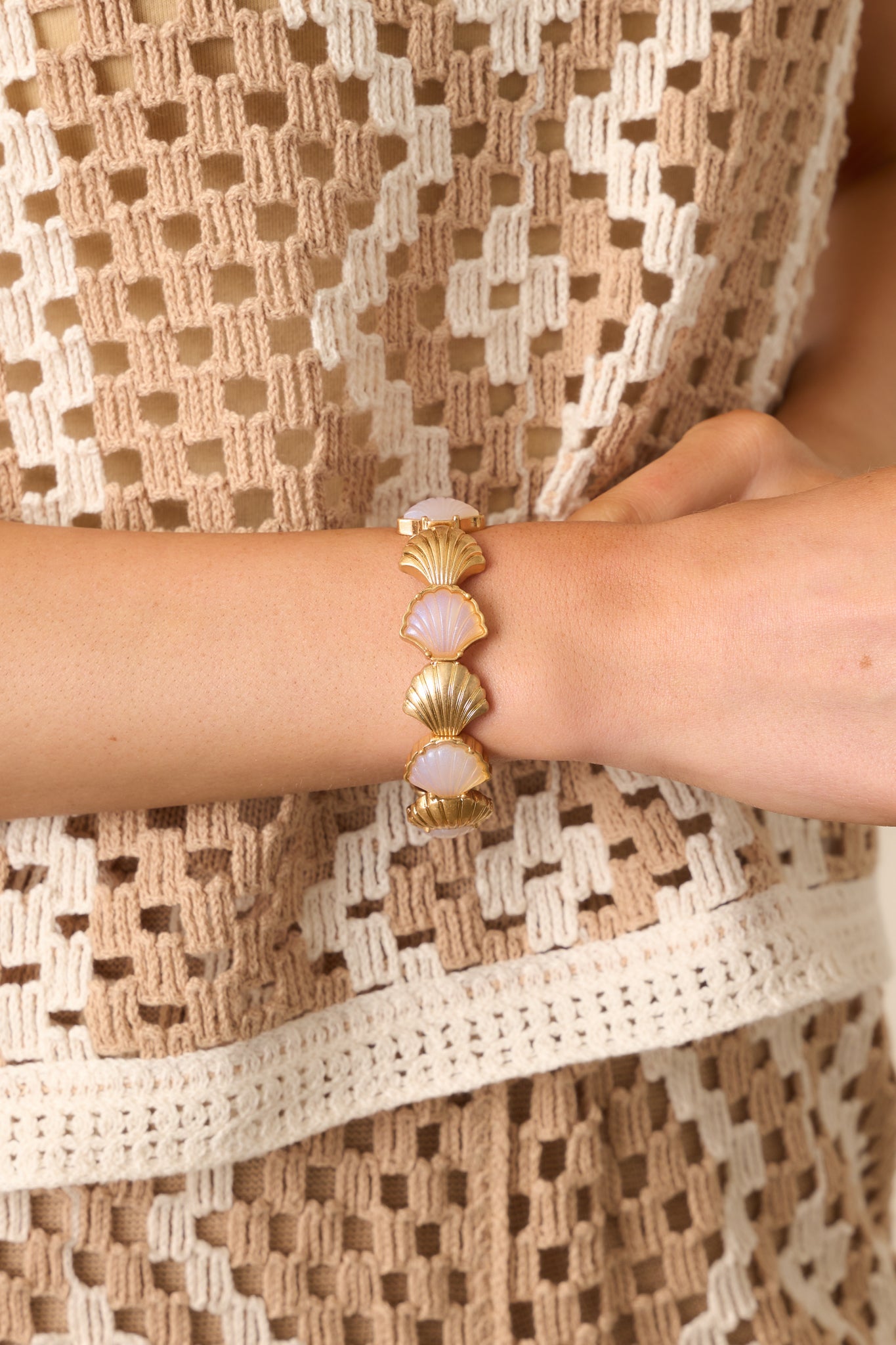 A partial view of the gold and pearlescent seashell bracelet, highlighting the contrast between the solid gold scallop shells and the pearlescent ones.