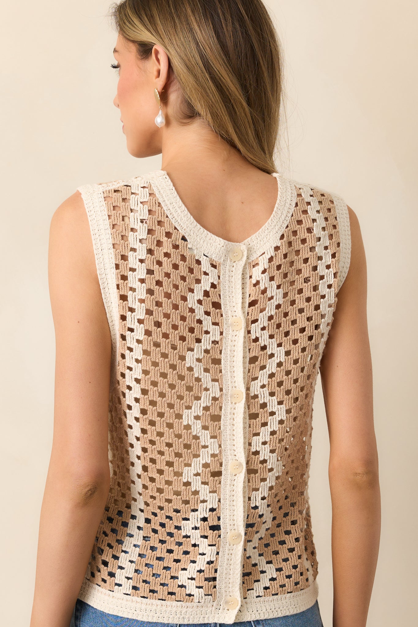 A view from behind of the tan and ivory geometric top showing the button closure and crochet texture.