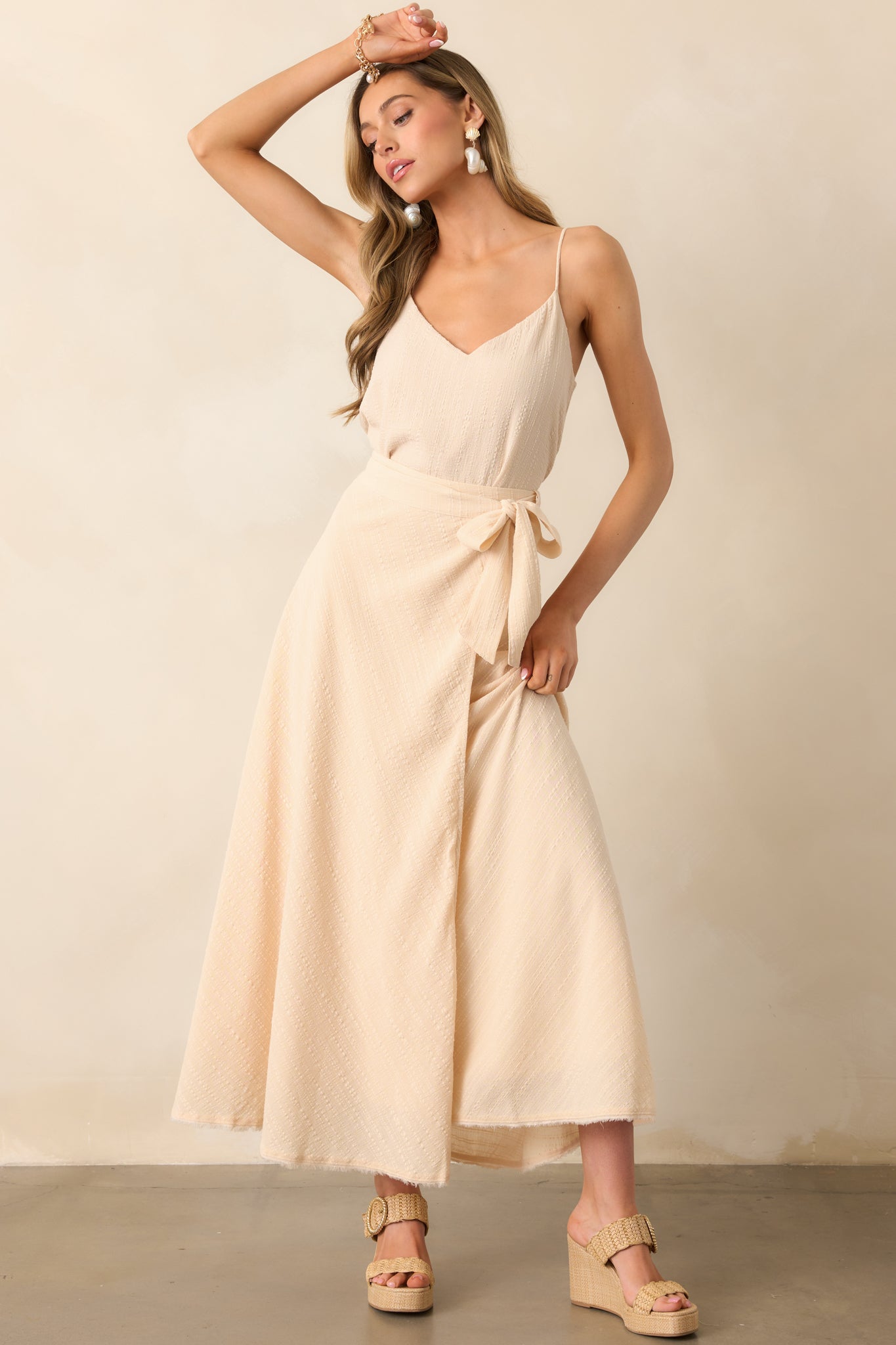 Beige skirt with a high-rise fit, wrap front, and raw-edge hem with light fraying for a casual look.