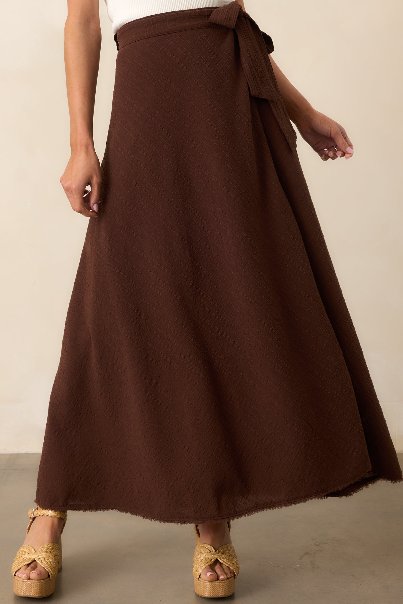 View of the brown skirt showing the raw-edge hem and subtle texture in the fabric