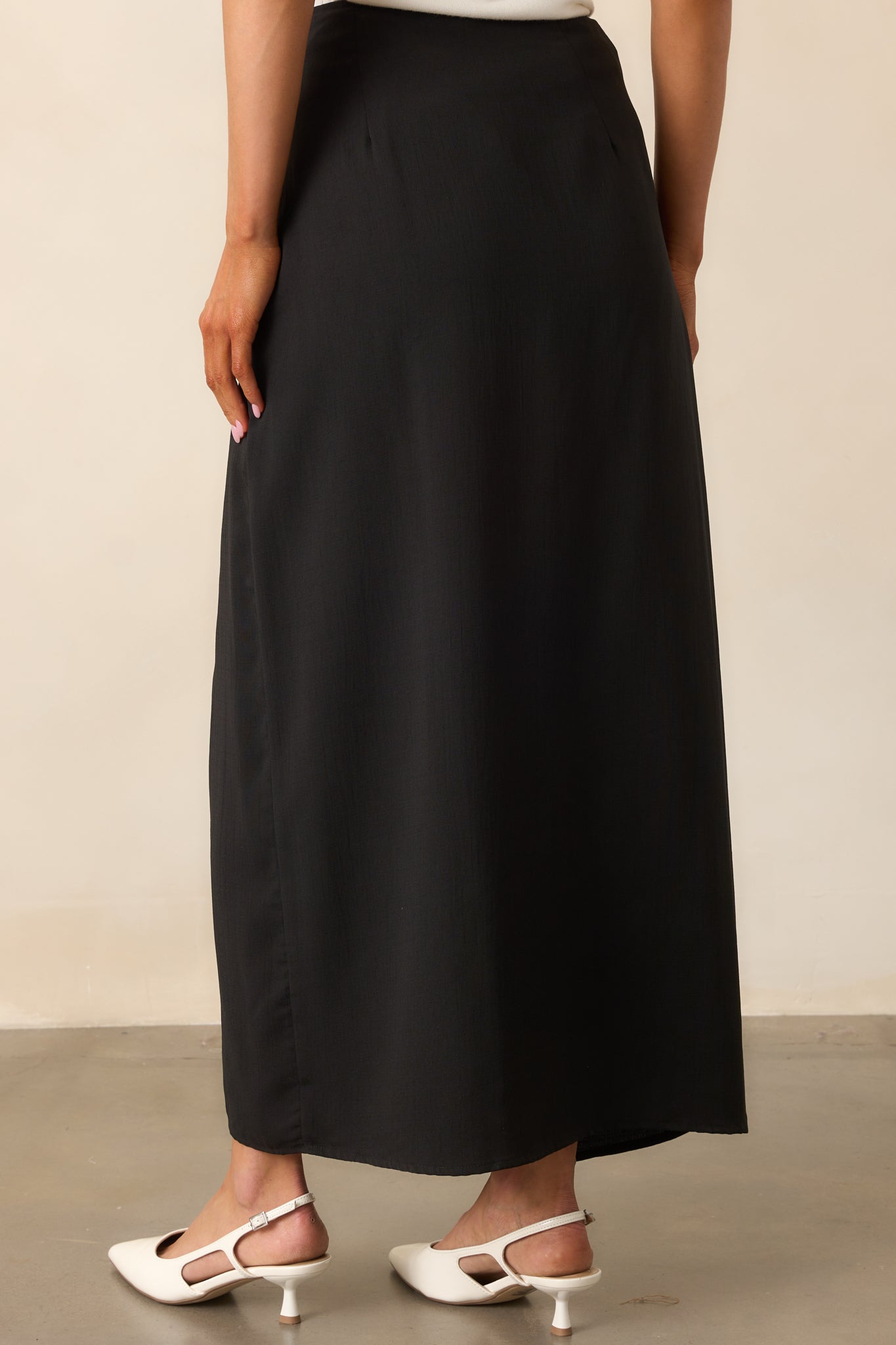 The black midi skirt viewed from behind, displaying its high-waisted fit and seamless construction.