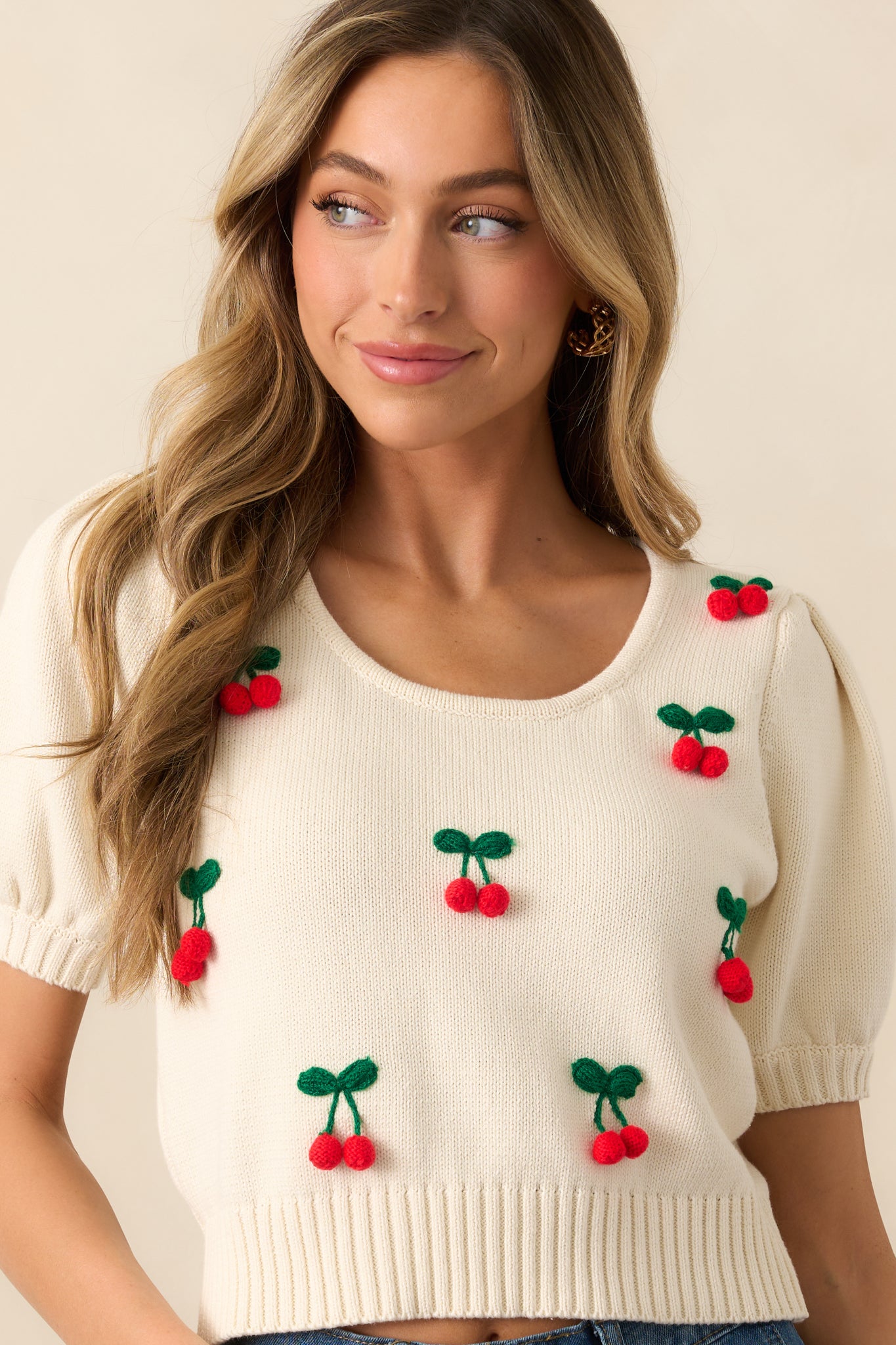 The scoop neckline and ribbed hemlines offer a structured yet casual feel, with 3D cherry appliqués adding a textured, whimsical detail to this ivory top.