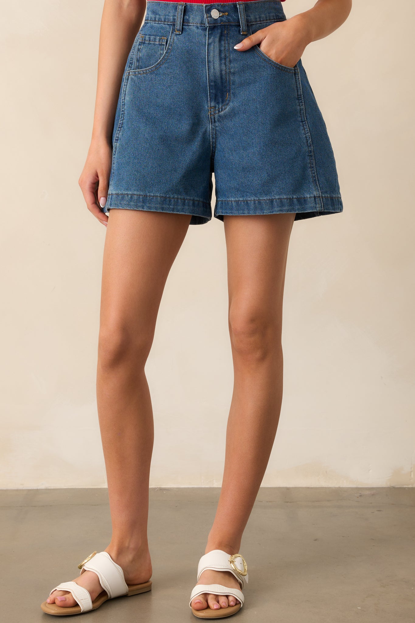 A closer view of the button and zipper closure, with functional belt loops adding a practical touch to these dark wash denim shorts.