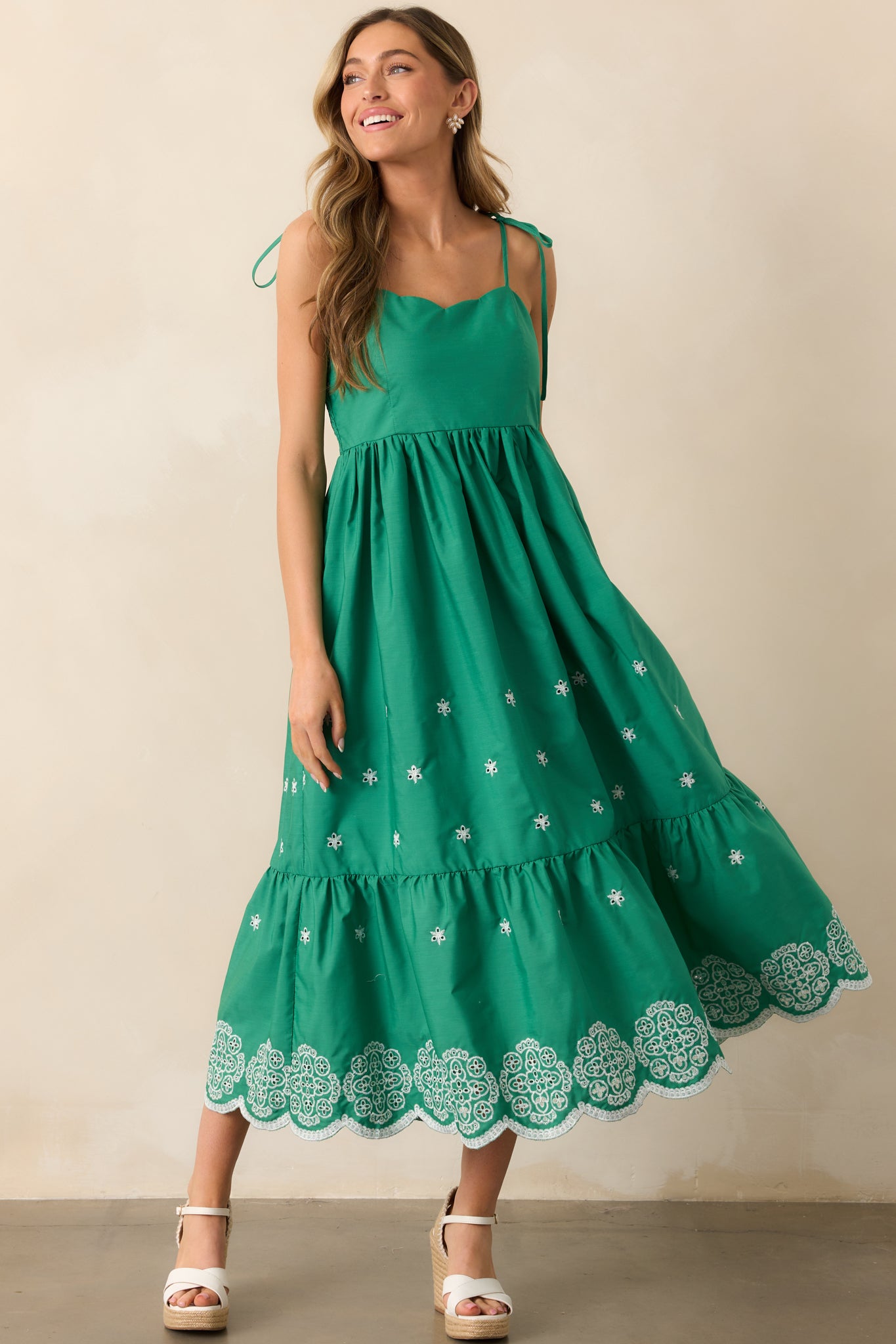 Featuring a scalloped sweetheart neckline and tiered skirt, this green midi dress boasts embroidered eyelet detailing for a soft, textured look.
