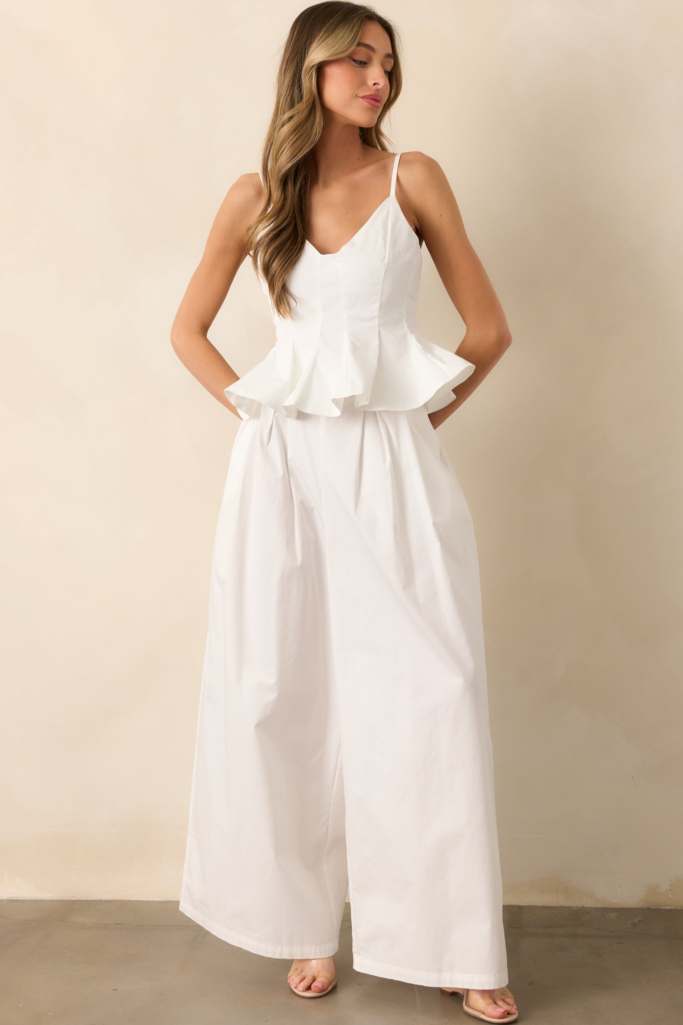 Front view of high-waisted white pants with wide-leg silhouette, pleated detailing, and functional pockets.