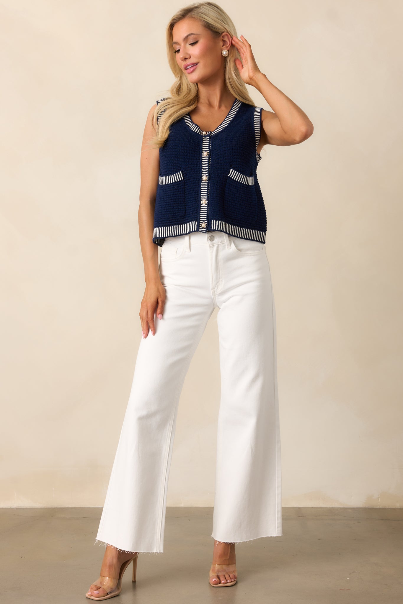 White jeans with a high-waisted design, featuring functional pockets, a classic button and zipper closure, a raw bottom hem, and a wide straight leg fit.