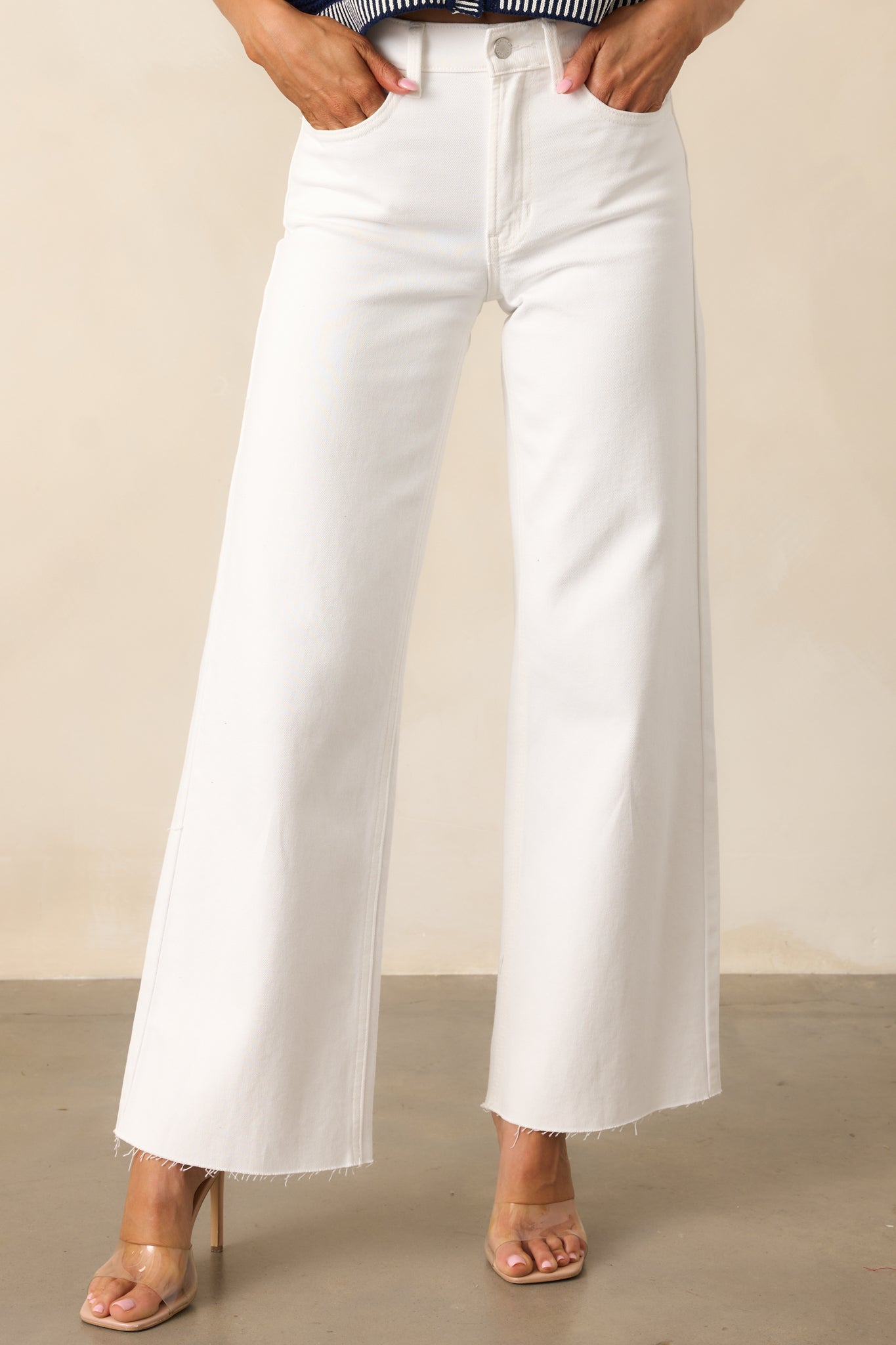 Close-up of the high-waisted design and classic button and zipper closure on the white jeans, highlighting the structured waist and sleek fit.