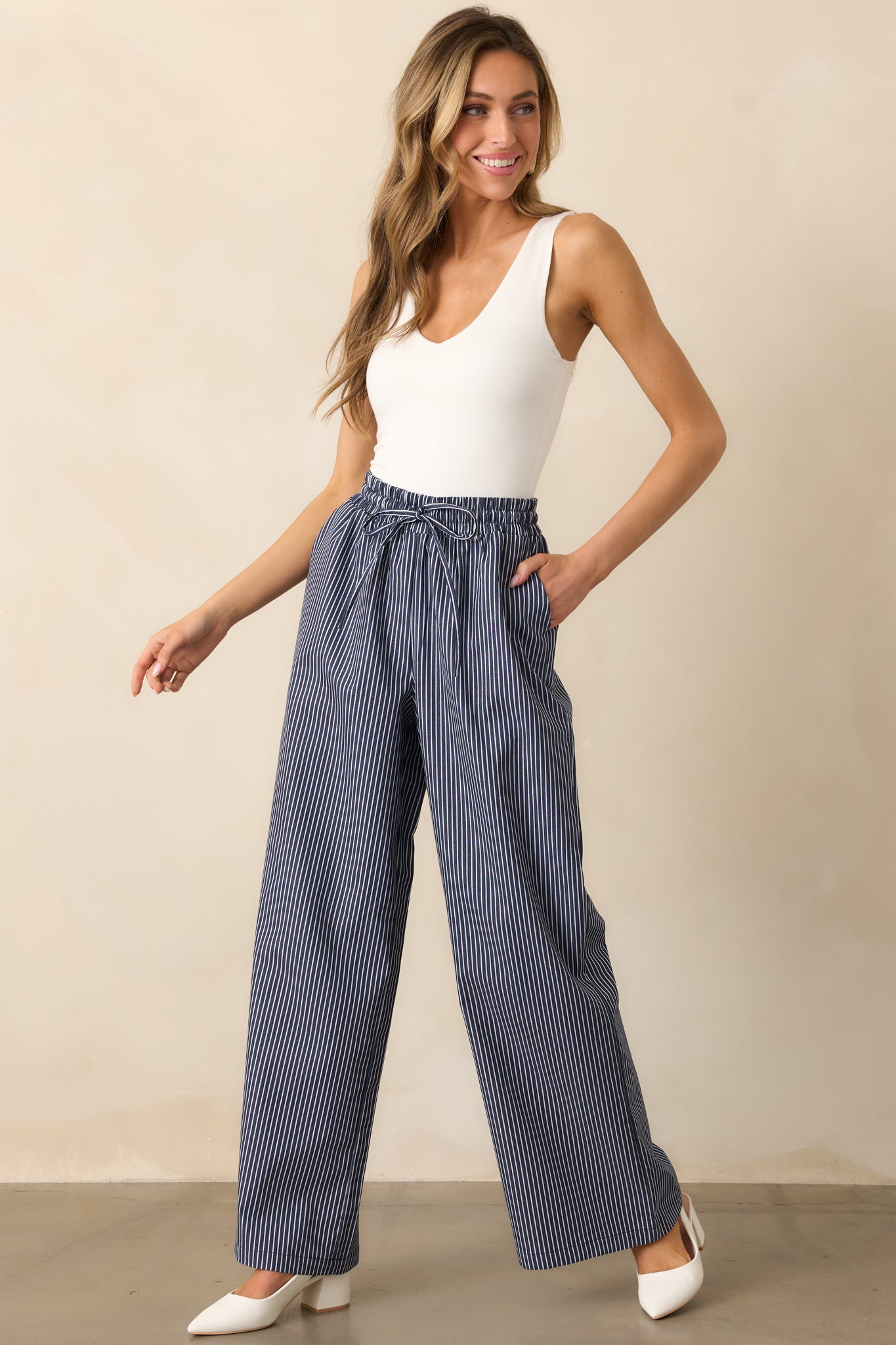 View of the navy pants with a relaxed fit, adjustable drawstring waistband, and functional pockets, completed with a subtle striped pattern.