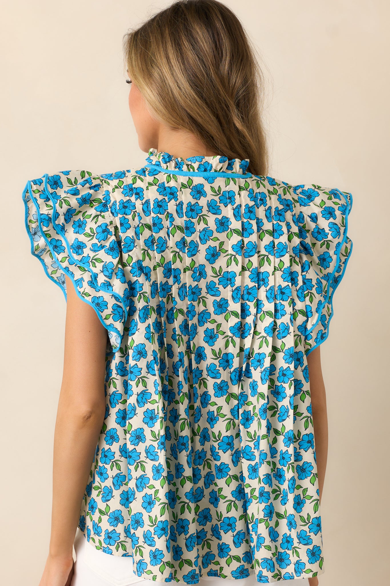 The back of the blue top, showcasing the continuous floral design and relaxed fit for a comfortable and stylish look.