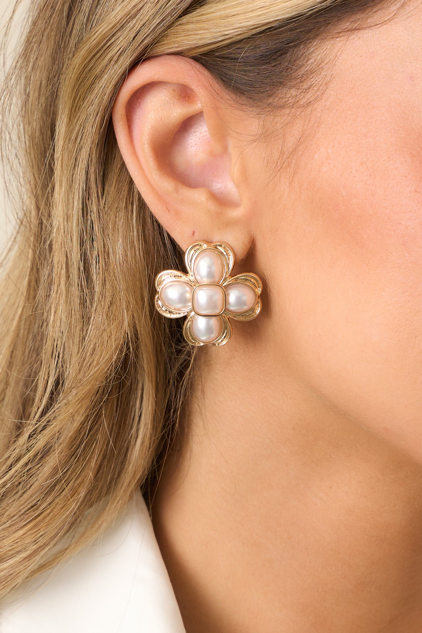 A closer view of the earrings, highlighting the large ivory faux pearls at each corner and the smooth square ivory pearl at the center, framed by rounded gold borders.