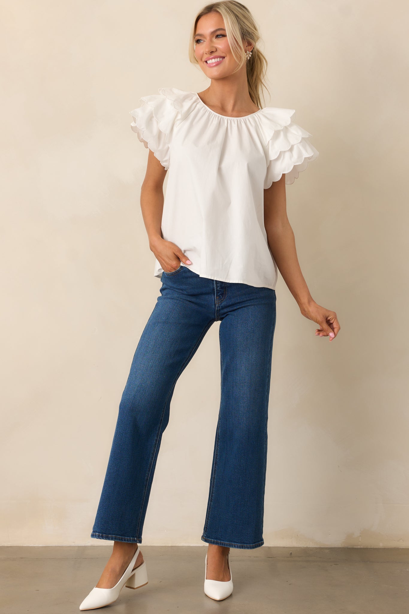 A light and airy white top with flutter sleeves, a scalloped hem, and a back keyhole closure for a refined yet relaxed design.