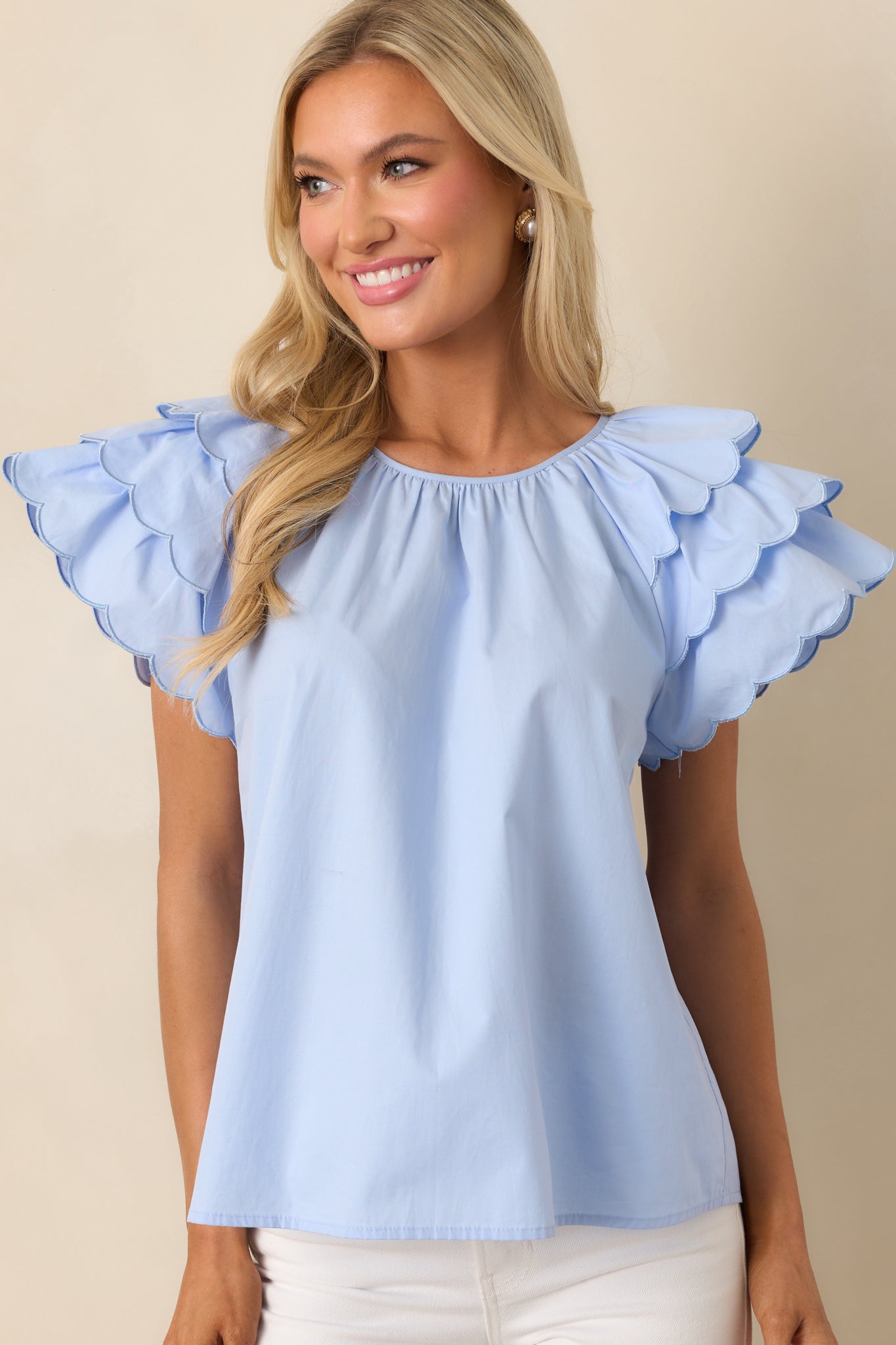 The round neckline and scalloped edges of this blue top add a subtle, elegant touch to the simple yet chic design.