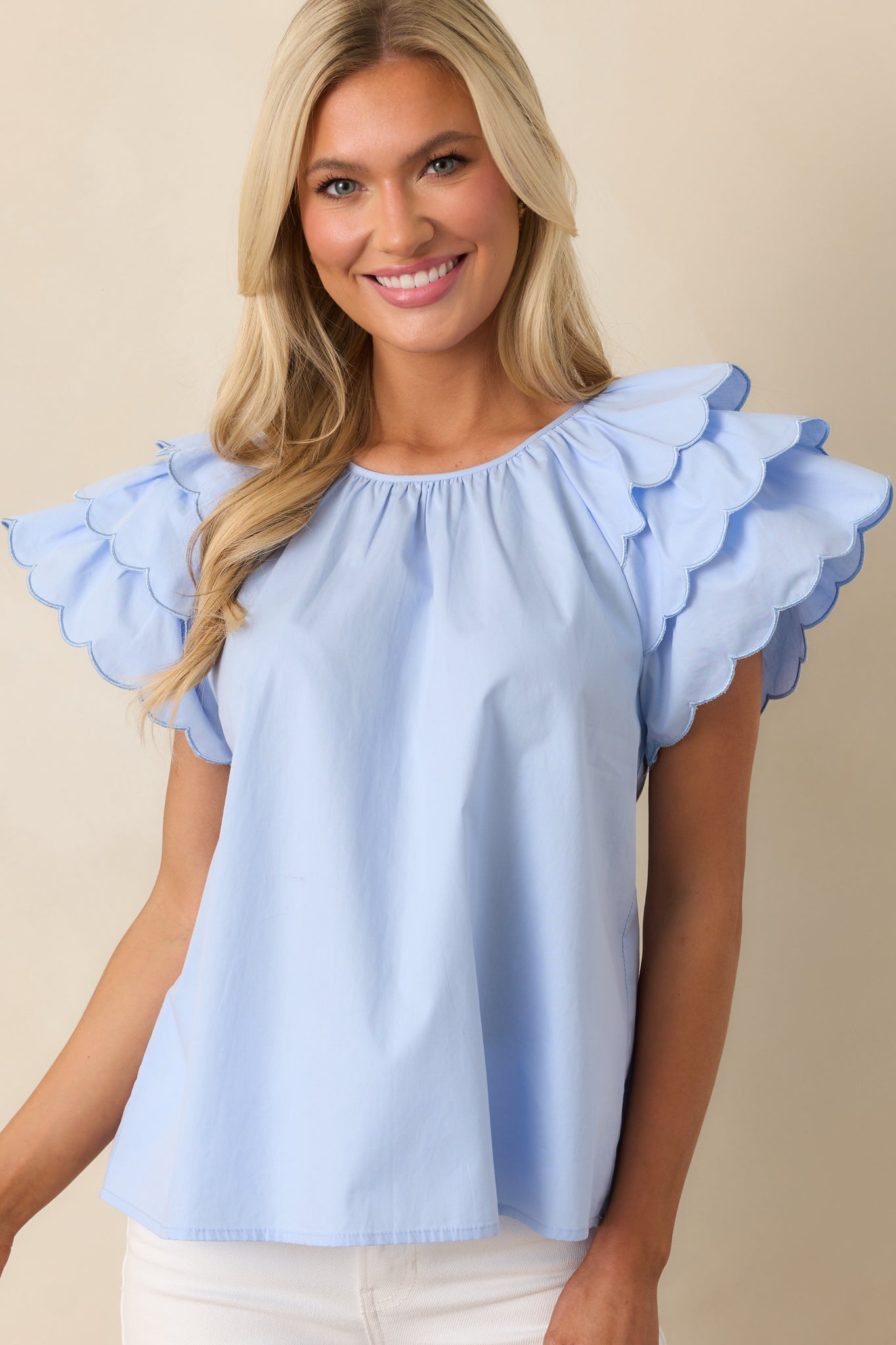 This blue top’s flutter sleeves and scalloped hems create a light, airy feel, enhancing the relaxed, comfortable fit.