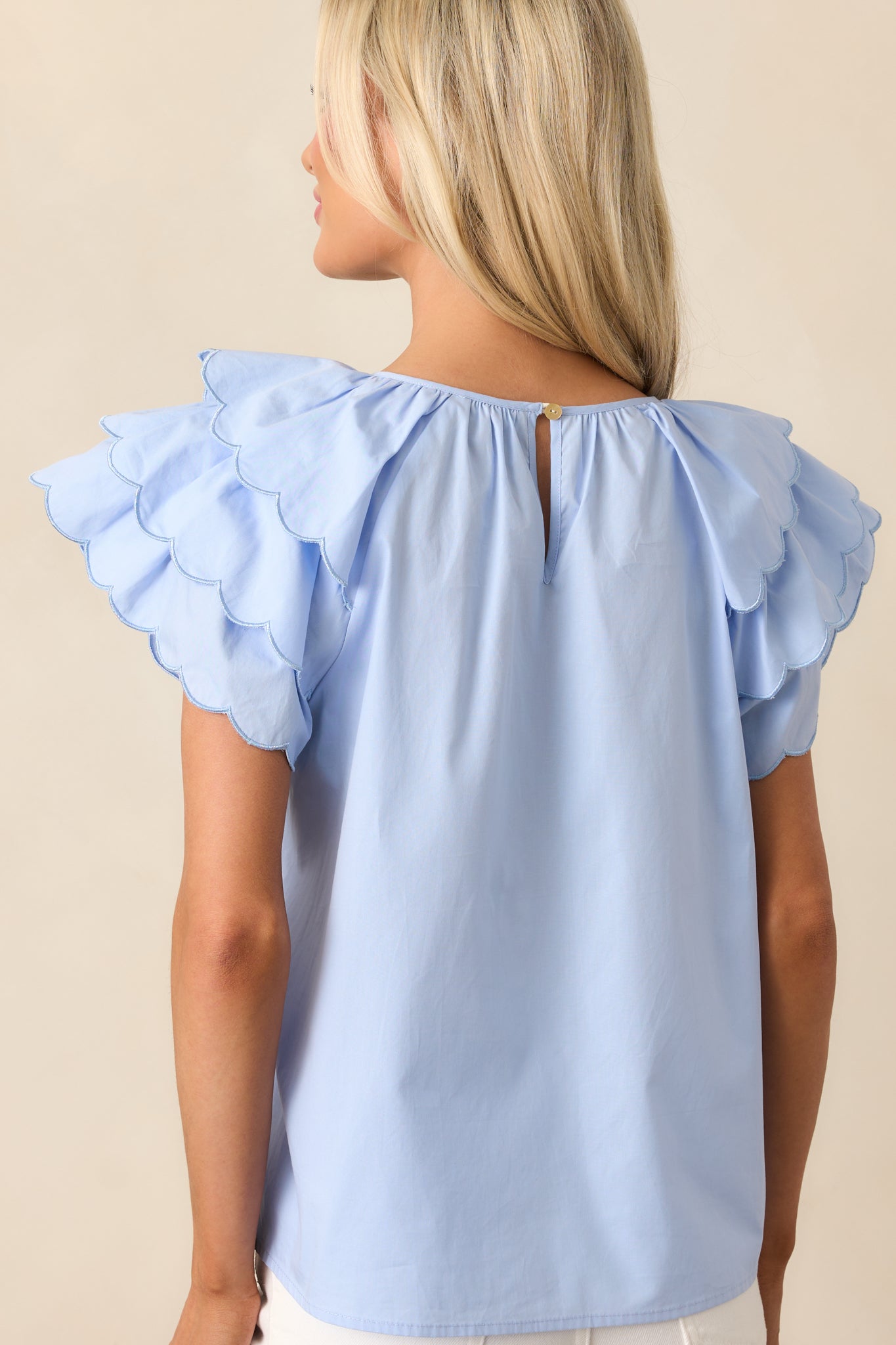 The back view of this blue top shows the elegant keyhole closure, adding a touch of sophistication to the soft, flowing design.