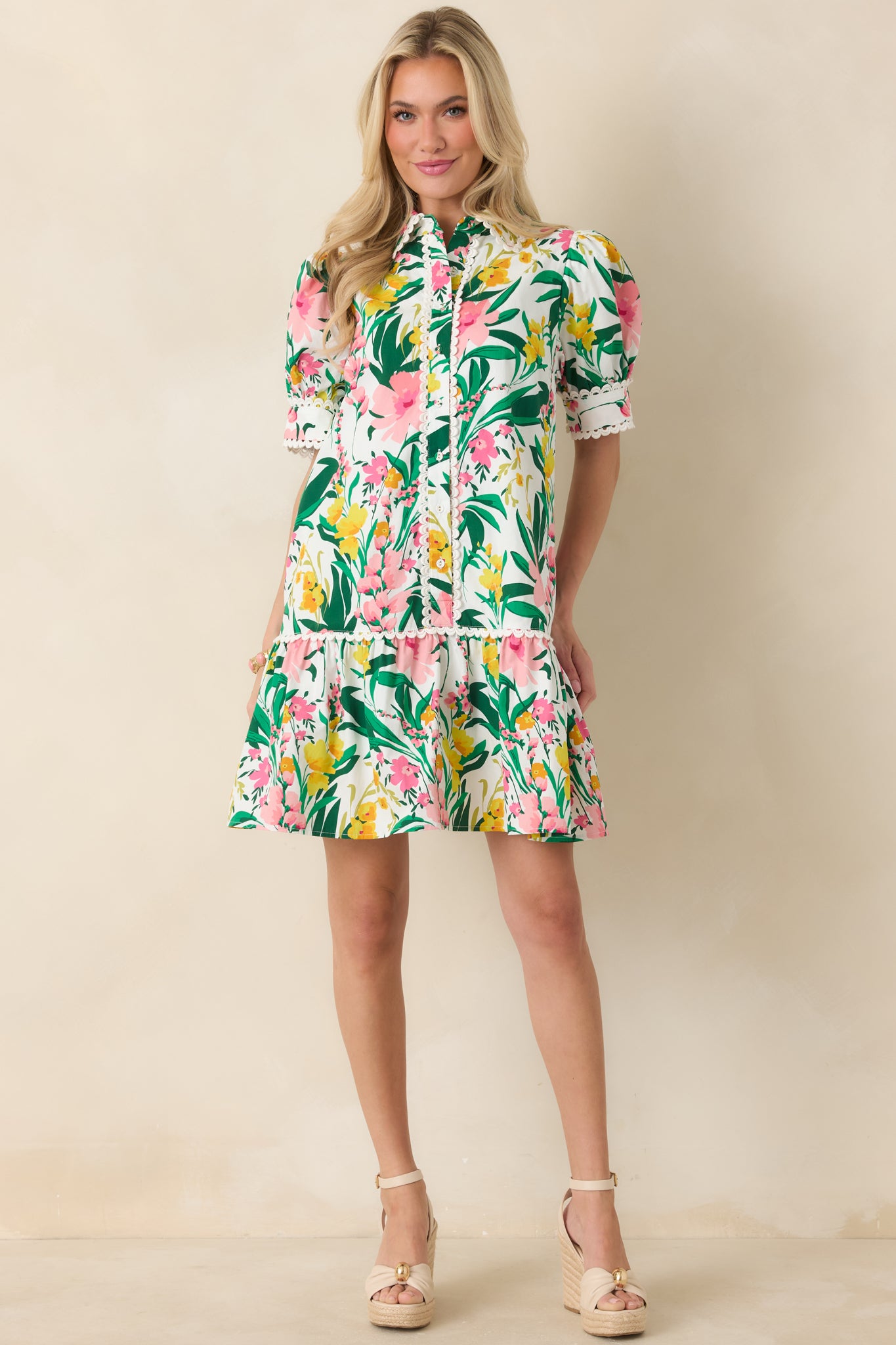 Bright floral cotton mini dress showcasing a button-front bodice, scalloped accents on neckline and sleeves, puff sleeves, and a playful ruffle hem.