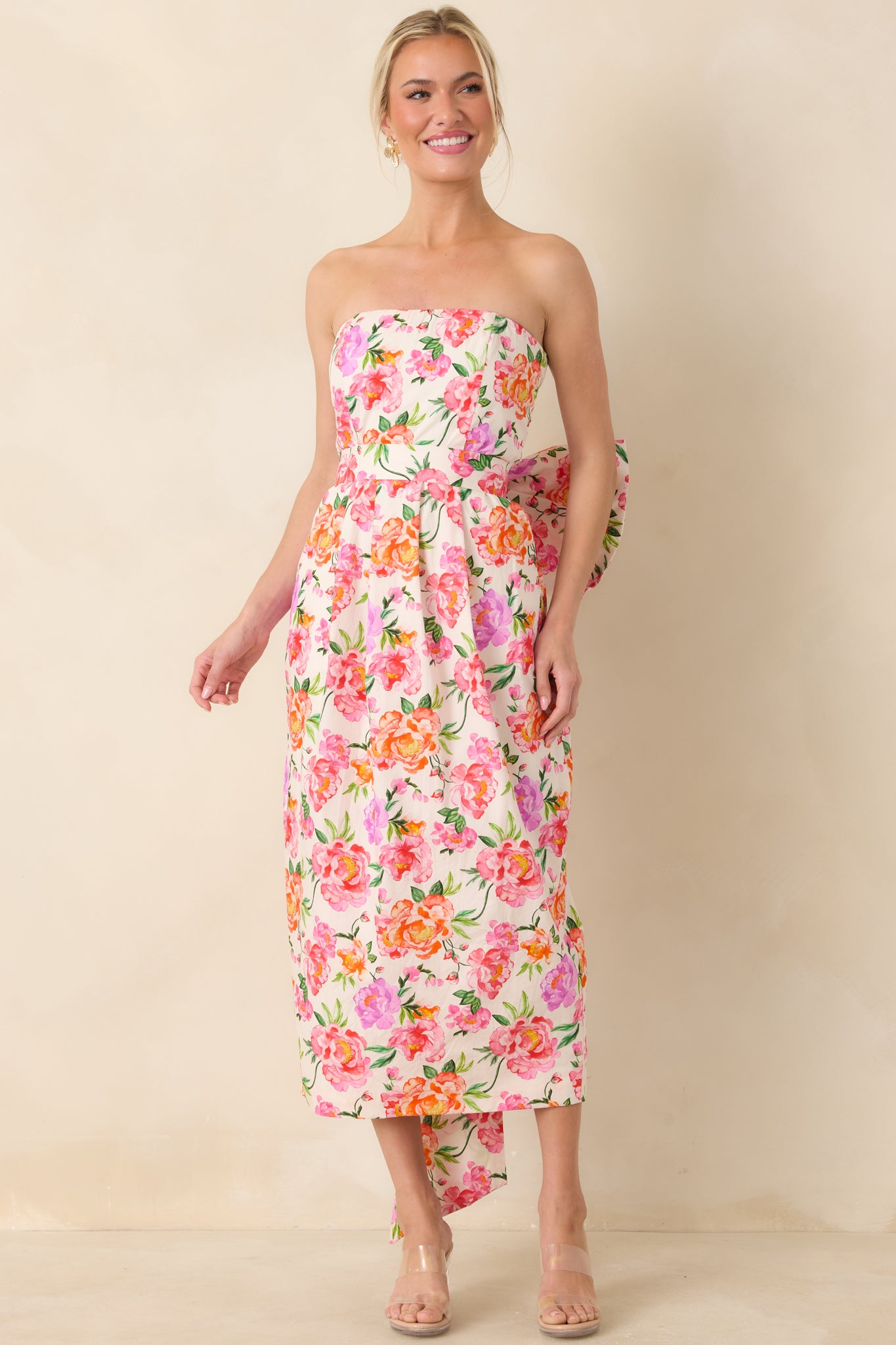Strapless cotton midi with bright pink floral pattern, tailored bodice, and sleek skirt, emphasizing a feminine, streamlined shape.