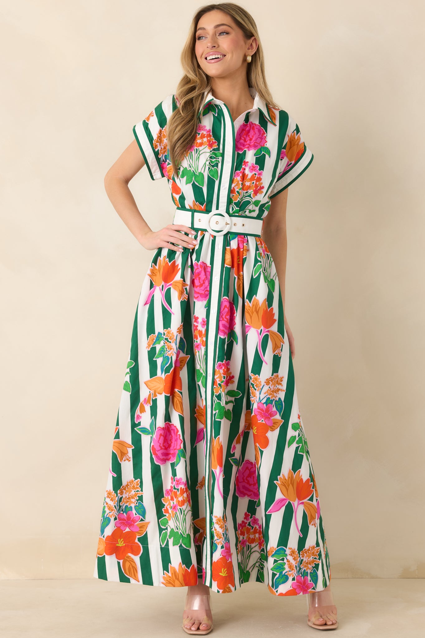 Maxi dress featuring bold green vertical stripes with pink, orange, and coral floral print, short cuffed sleeves, and a coordinating waist belt.