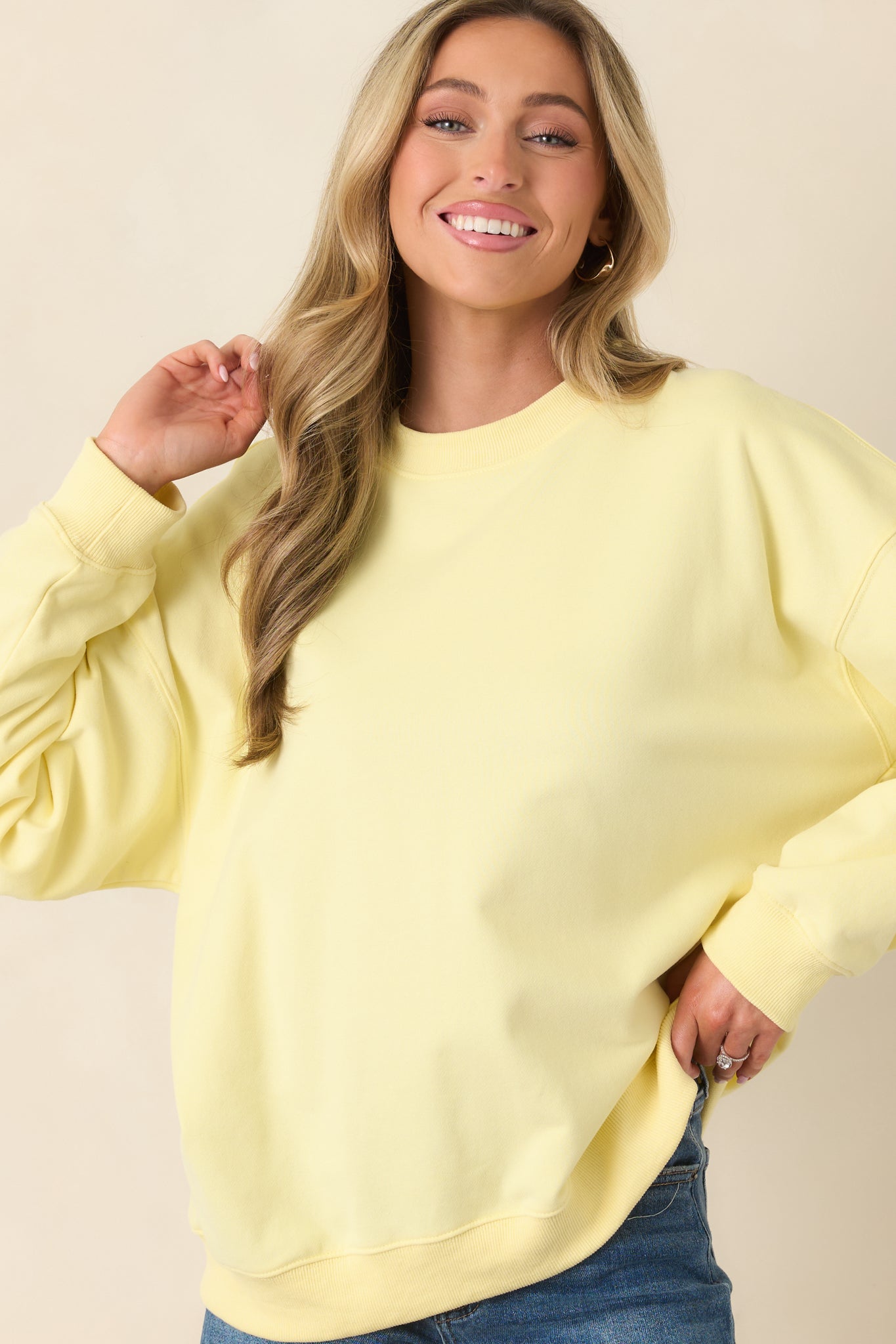 Front crop of yellow crewneck sweatshirt showing ribbed crew neckline and soft knit fabric.