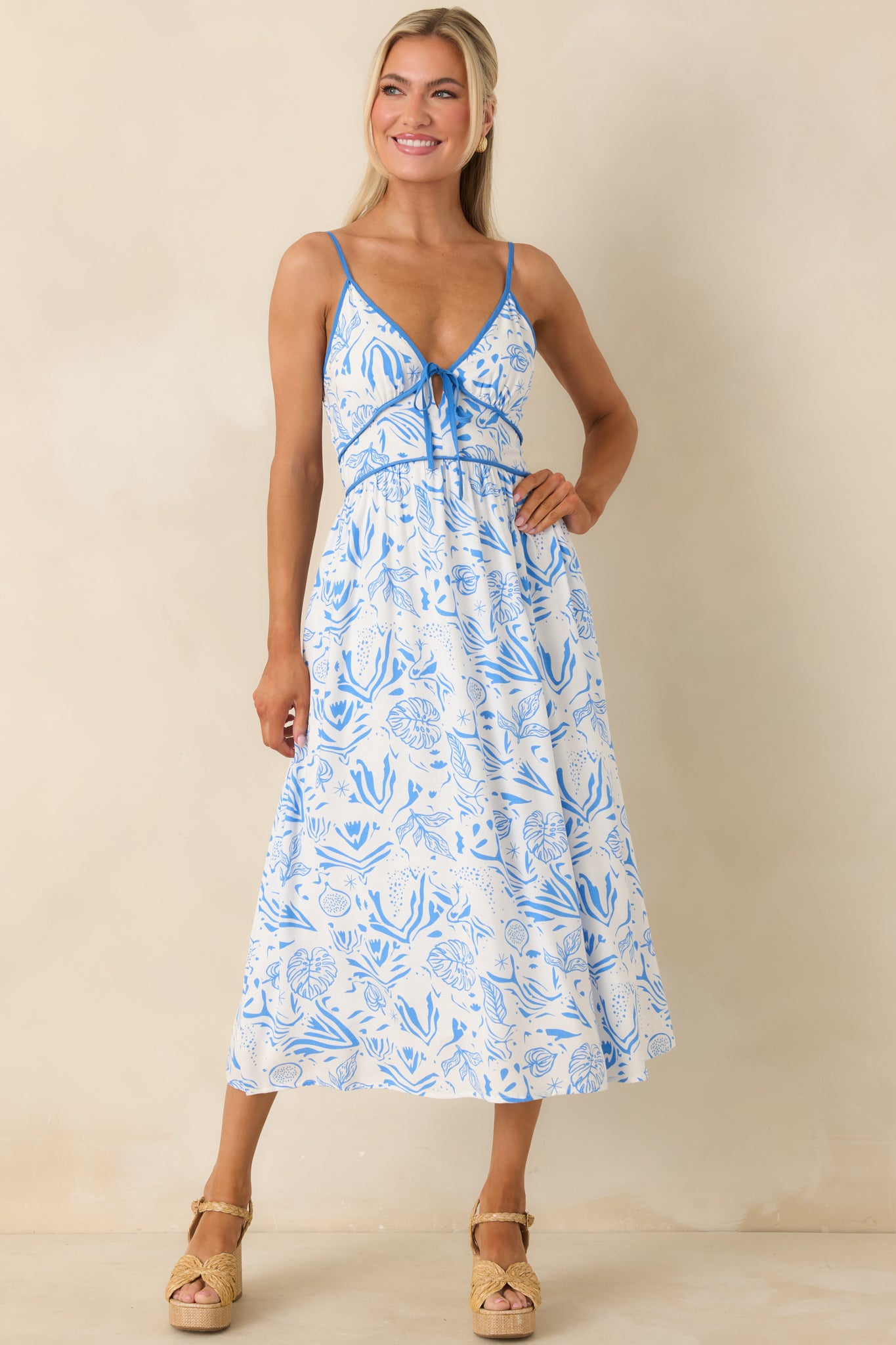 Midi dress featuring blue piping trim under the bust, decorative self-tie bow, and functional side pockets.