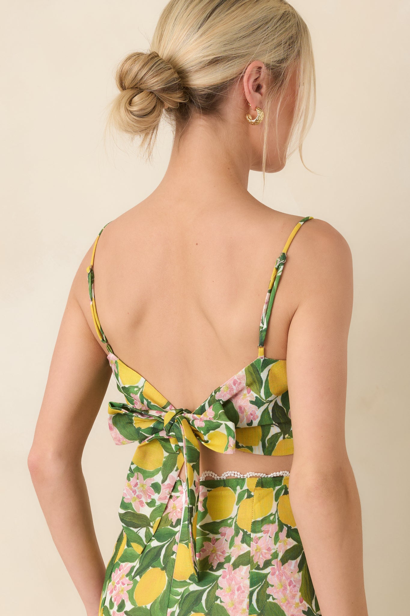 Rear view of the yellow multi cropped camisole featuring a smocked back with tie closure and adjustable spaghetti straps for a custom fit.