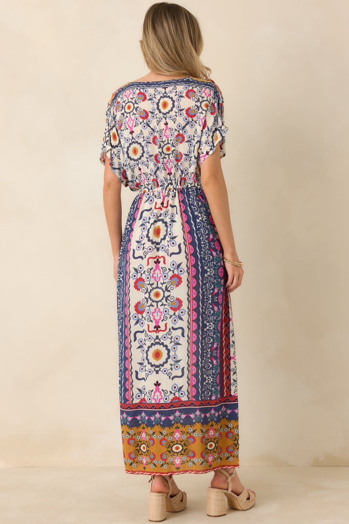 Back view of the dress displaying the continuous patchwork print, adjustable drawstring detail from behind, and flowy fit through the back hem.